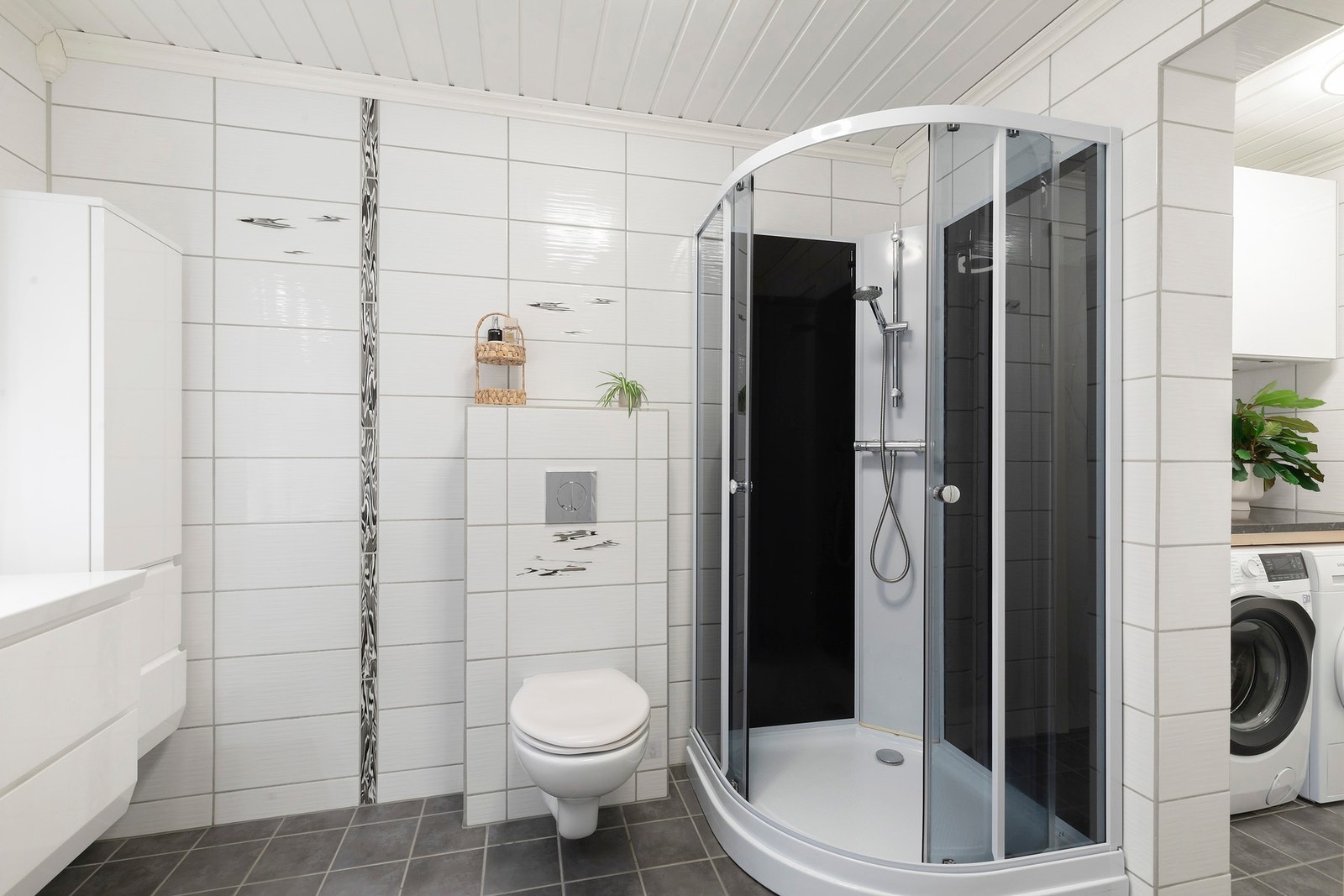 Flislagt baderom (2012) med påfølgende vaskerom i 1. etasje. Badet er utstyrt med dusjkabinett, veggmontert WC, servant og servantskap. Mekanisk avtrekk. Galleribilde