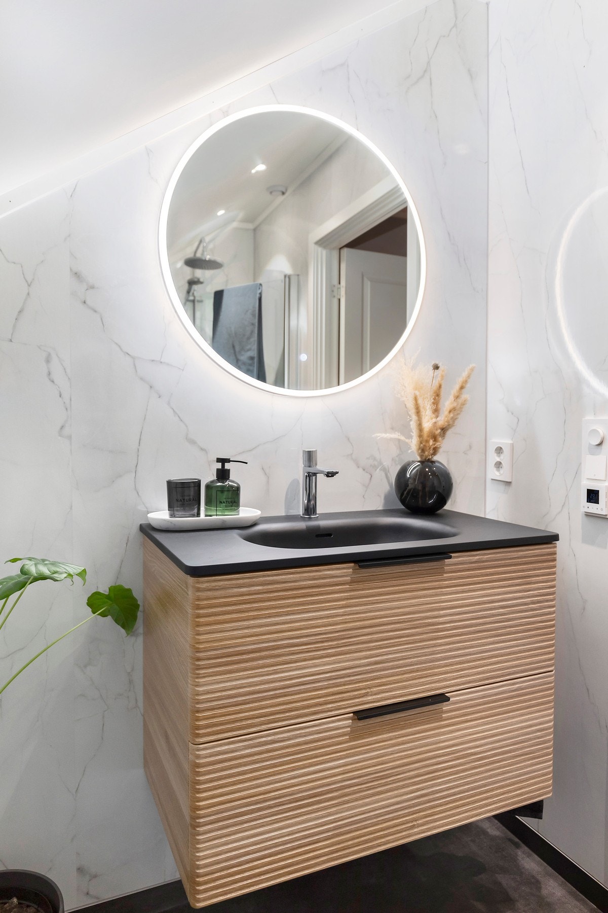 Badet er utstyrt med innfellbare dusjdører, vegghengt WC og servant med underskap. Galleribilde