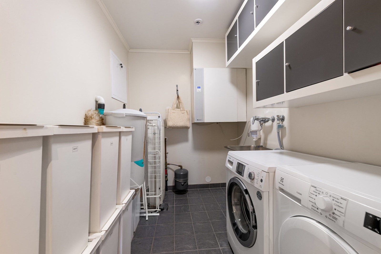 Vaskerom med flisbelagt gulv, gulvvarme og god plass til både vaskemaskin og tørketrommel - rommet er byggemeldt som bod Galleribilde