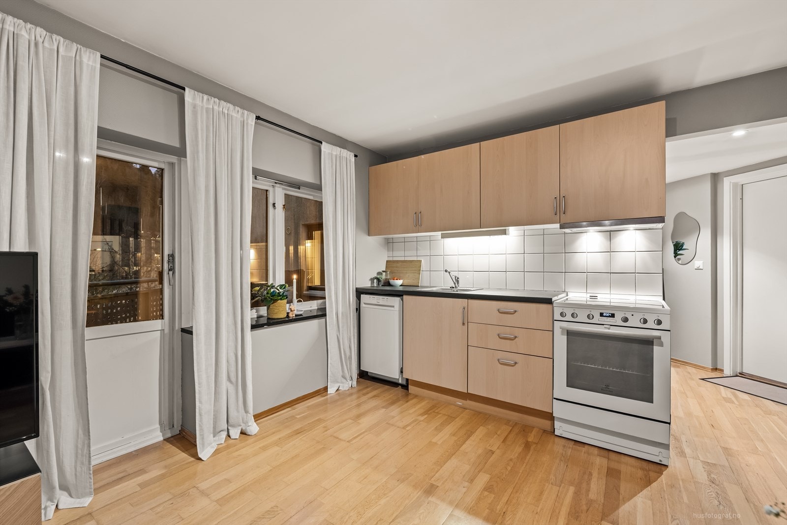 Kjøkkenet har innredning med glatte fronter, benkeplate av laminat og fliser mellom benkeplate og overskap. Galleribilde