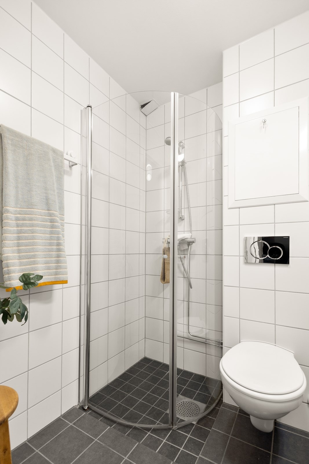 Badet er utstyrt med servant med underskuffer, speilskap med lys, veggmontert toalett samt dusjhjørne med innfellbare dusjvegger i glass. Galleribilde