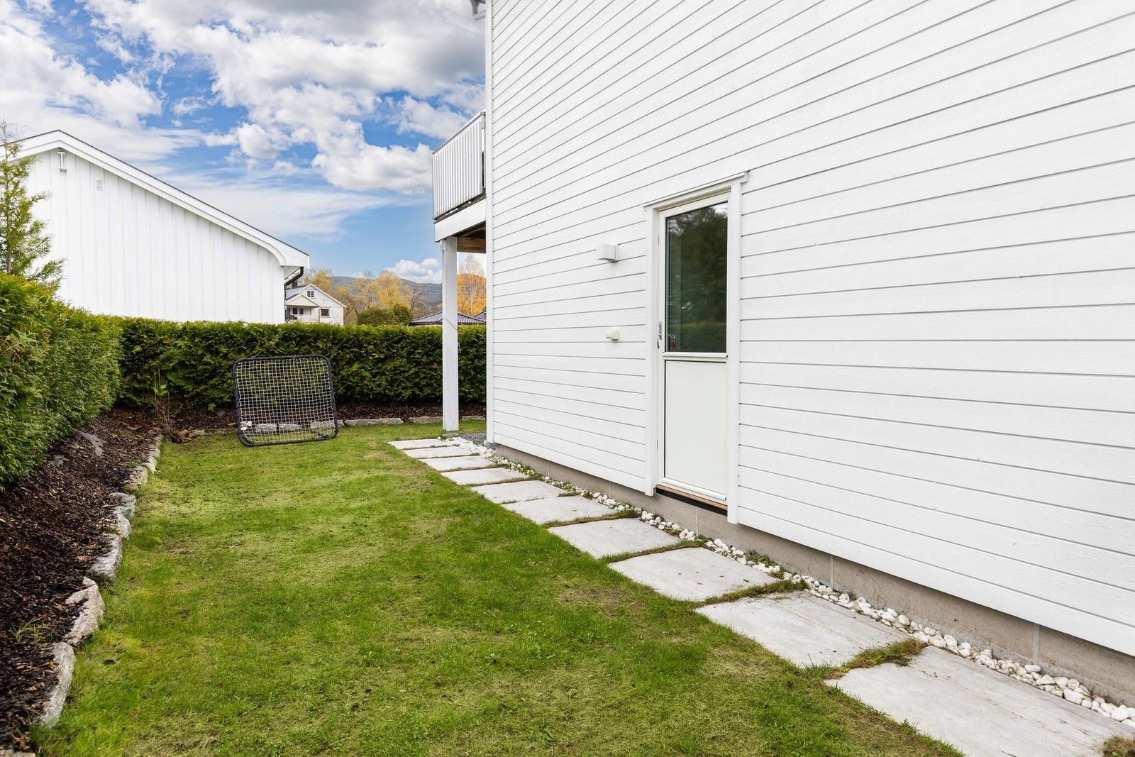 Videre er hagen pent opparbeidet med gress og hekk som omkranser eiendommen. Galleribilde