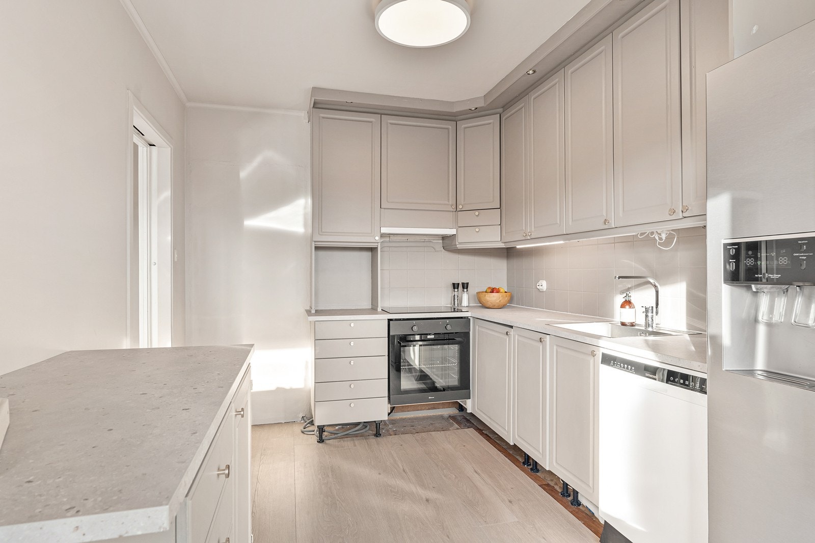 Innredningen har profilerte fronter og laminat benkeplate, med fliser mellom benkeskapene som gir et rent og klassisk uttrykk. Galleribilde