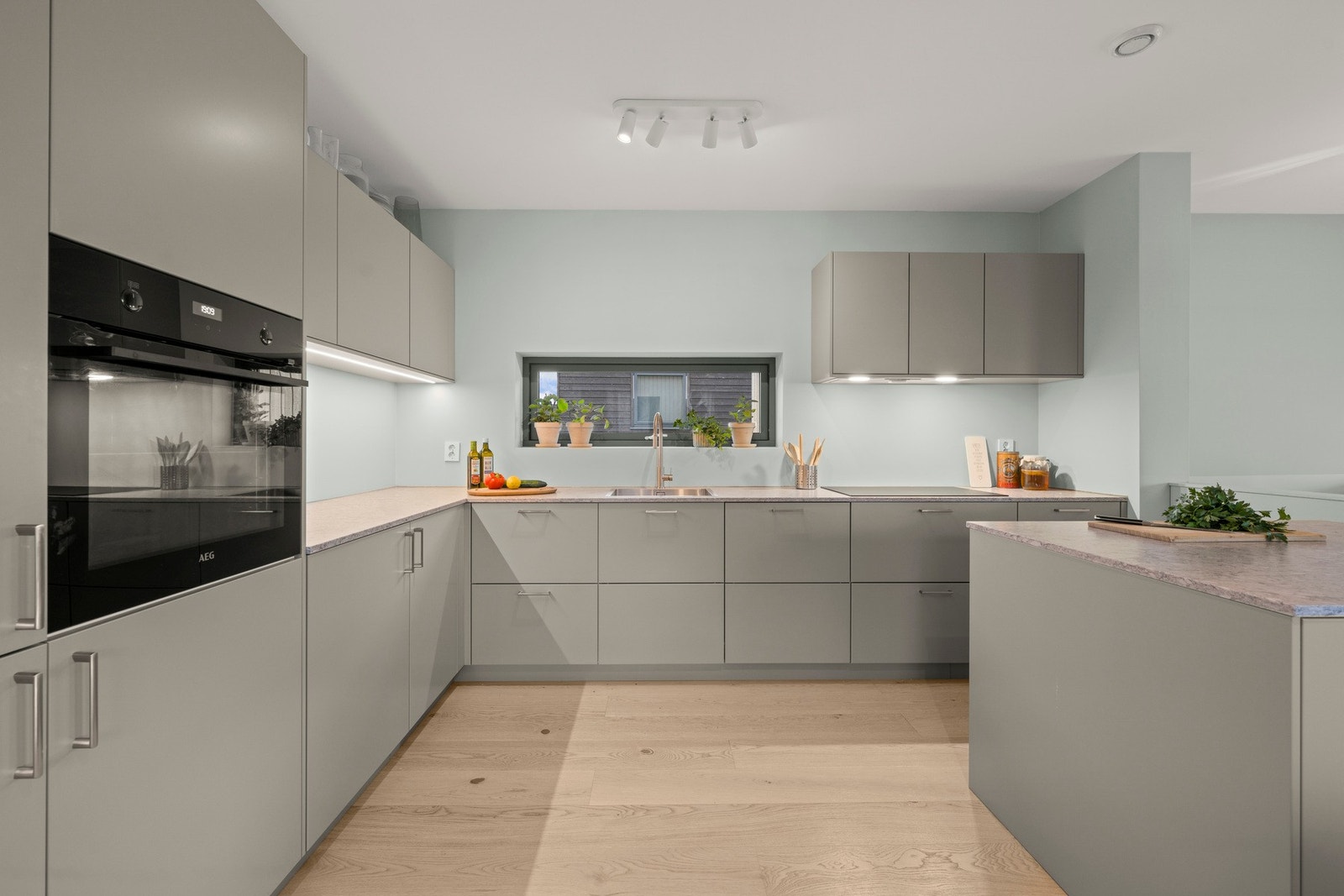 Kjøkkeninnredning med glatte fronter og komposittstein benkeplate levert av Drømmekjøkkenet. Galleribilde