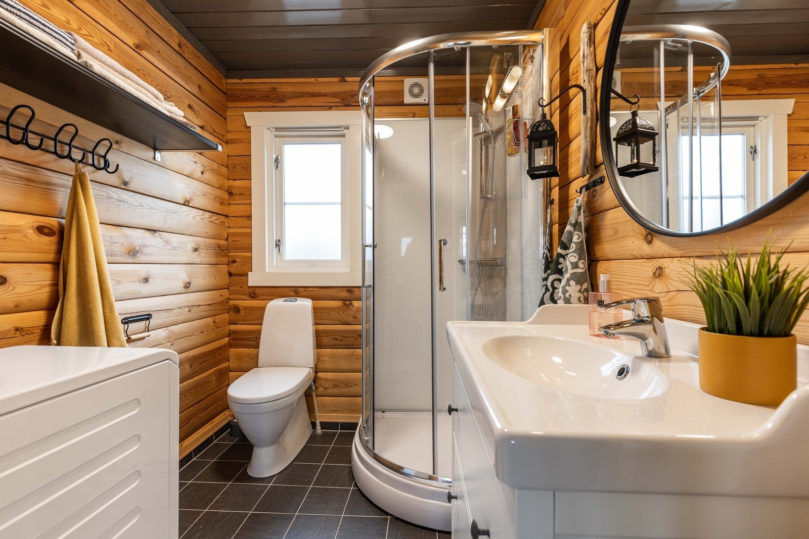 Hyggelig baderom som inneholder servant, dusjkabinett, wc og opplegg for vaskemaskin. Galleribilde