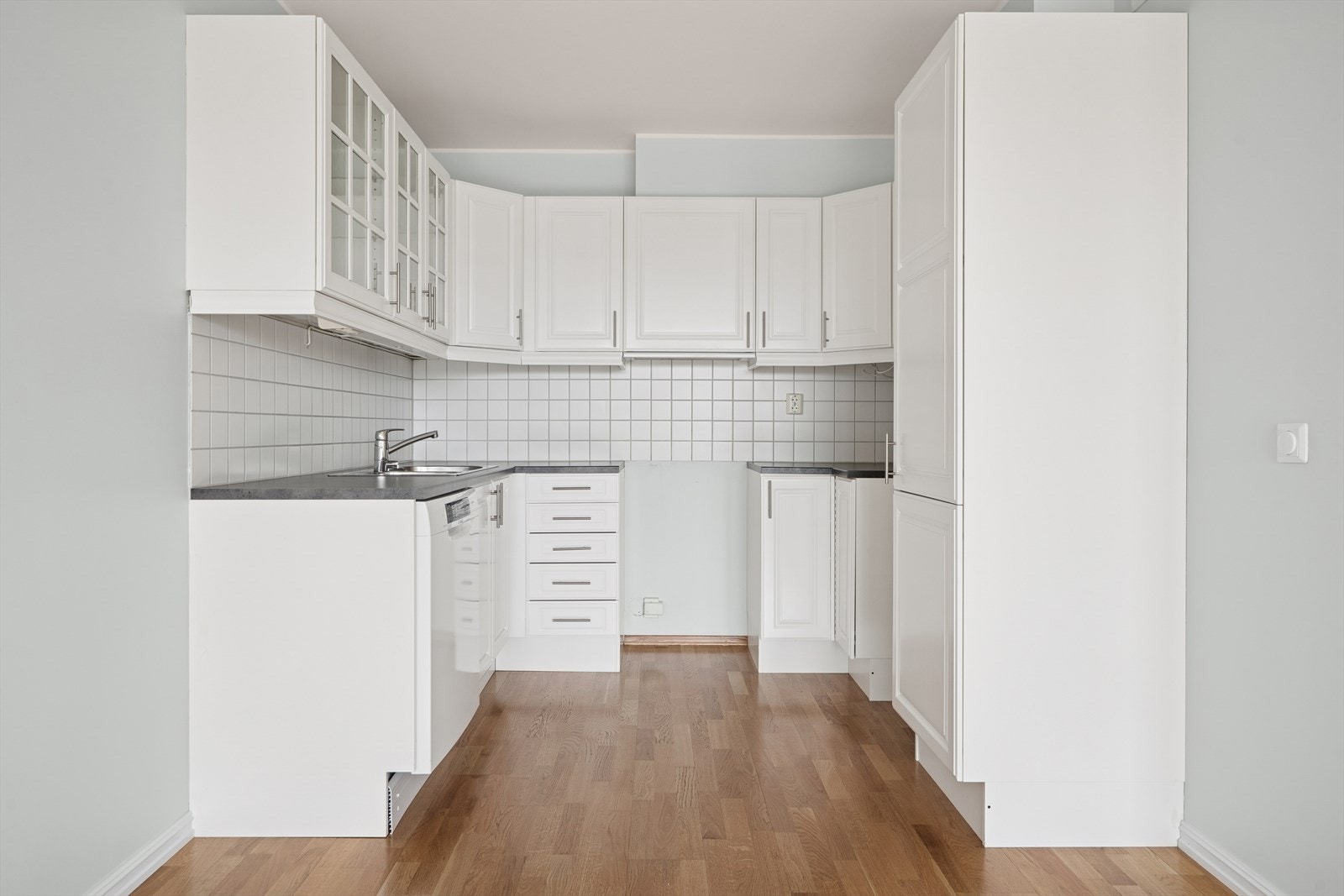 Heltre kjøkkeninnredning fra Sigdal i hvitmalt utførelse (opprinnelig eikefronter). Laminat benkeplate med nedfelt dobbel oppvaskkum. Det er avsatt plass for komfyr, oppvaskmaskin og kjøleskap. Det er rikelig med skap og benkeplass! Galleribilde