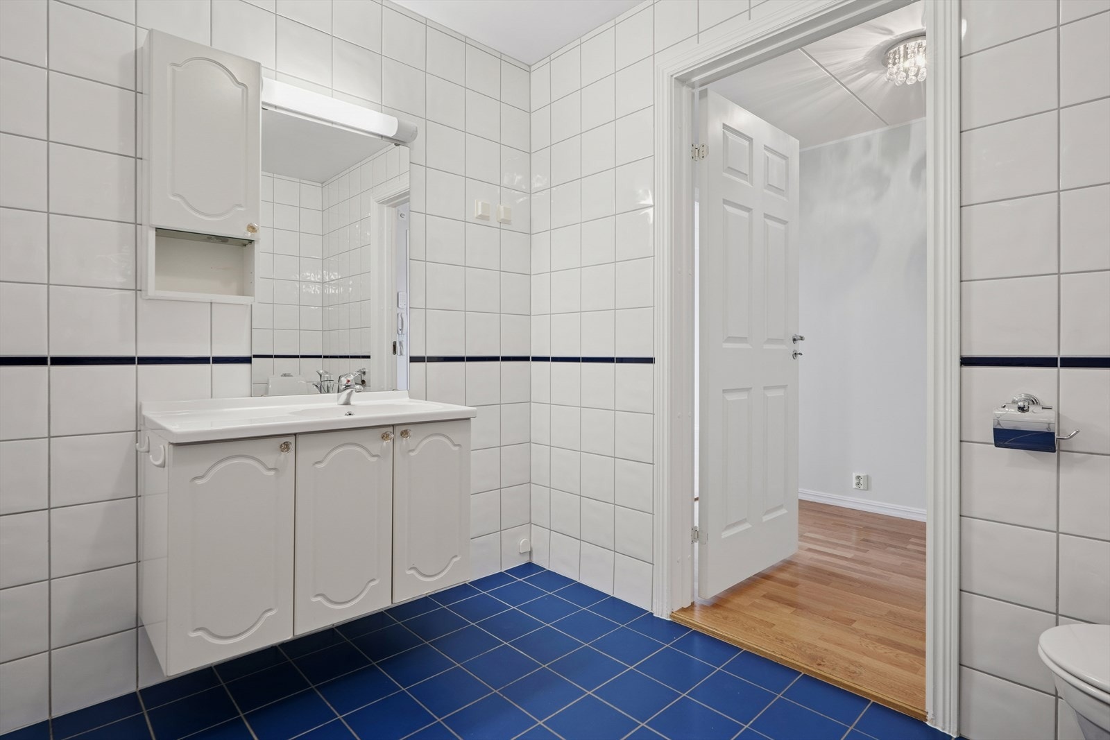 Flislagt baderom med varmekabler i gulv fra byggeår. Rommet er innredet med dusjhjørnet uten tildekking, toalett, servantinnredning, speil på vegg over servant. Det er også opplegg for vaskemaskin. Galleribilde