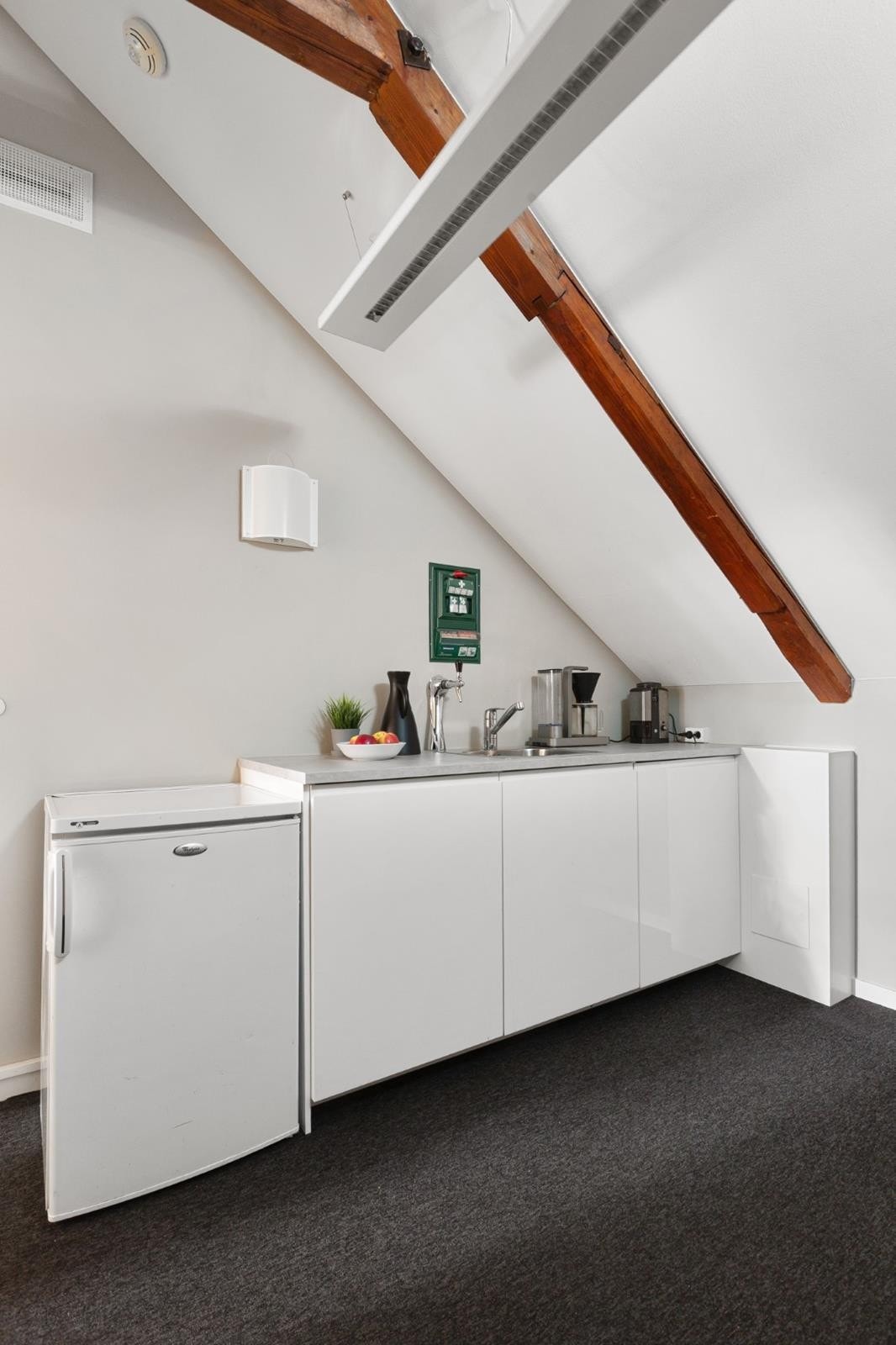 Lun og praktisk kjøkkenkrok i toppetasjen - perfekt for en kaffepause eller en rask lunsj. Med kjøleskap, kaffemaskin og enkel benkplass får du alt du trenger lett tilgjengelig i et hyggelig arbeidsmiljø. Galleribilde