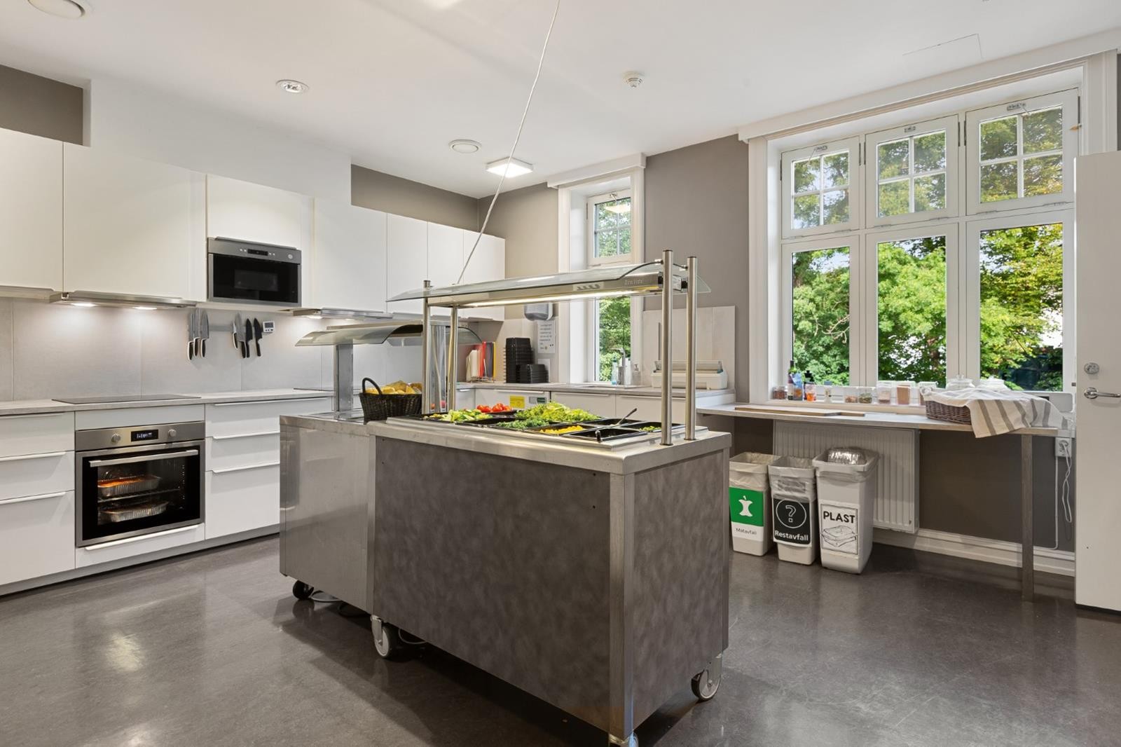 Velutstyrt kantine med moderne kjøkken, serveringsstasjon og store vindusflater - perfekt for å skape et sosialt samlingspunkt og tilby ansatte gode lunsjopplevelser i lyse og trivelige omgivelser. Galleribilde