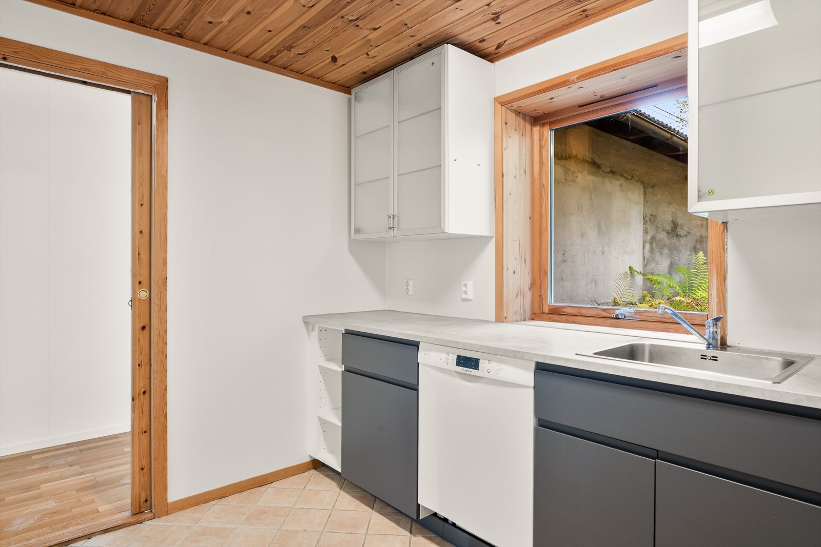 Kjøkken har fliser på gulv og malte vegger. Skyvedør mot allrom/møterom Galleribilde