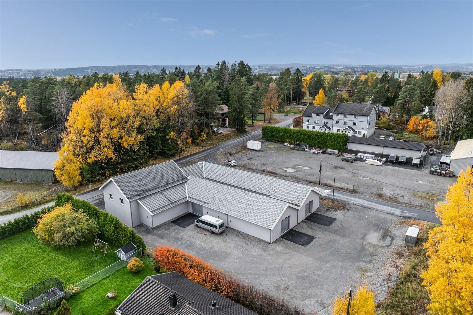 Eiendommen er flat og opparbeidet med asfaltert oppstillingsplass ved adkomst, gruset område rundt verkstedhaller med asfalt foran kjøreporter. Galleribilde