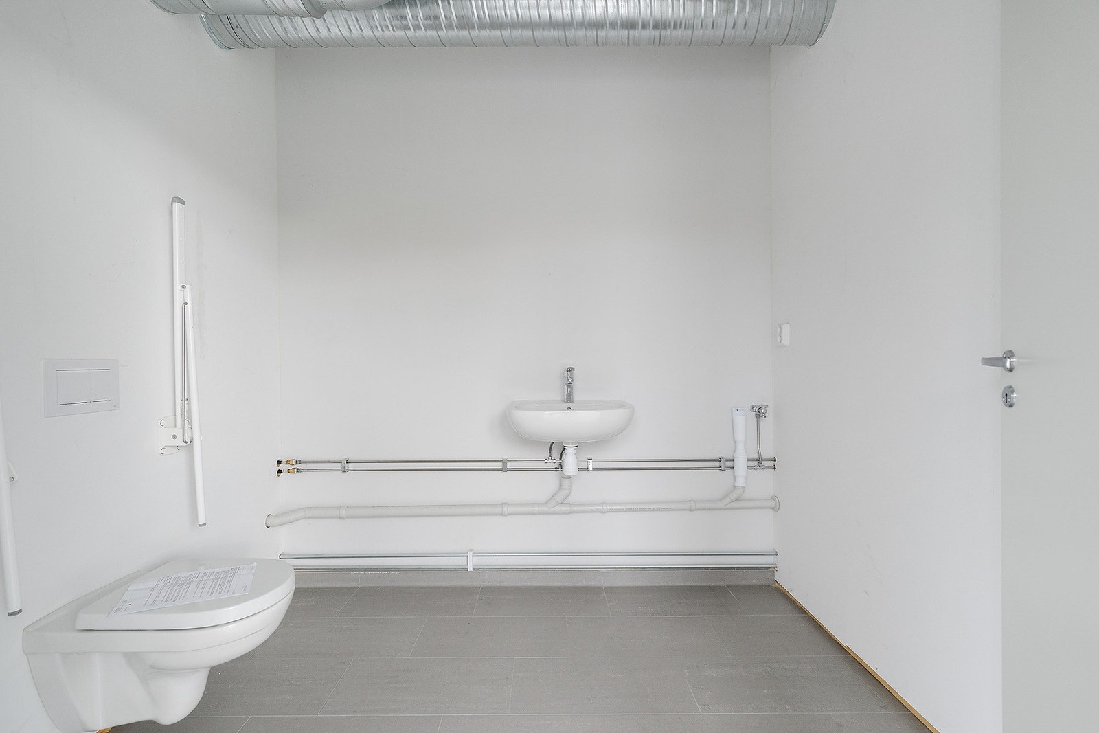 Lokalet er utstyrt med to separate sanitærrom, hvor det ene er tilrettelagt for rullestolbrukere. Begge rommene har moderne utførelse med grå fliser på gulv, og er innredet med servant og toalett. Galleribilde