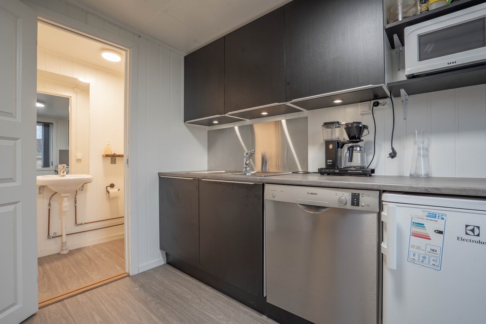 Moderne kjøkken med integrerte hvitevarer og praktisk belysning. Tilknyttet toalett med stilrent design og funksjonelle løsninger. Galleribilde