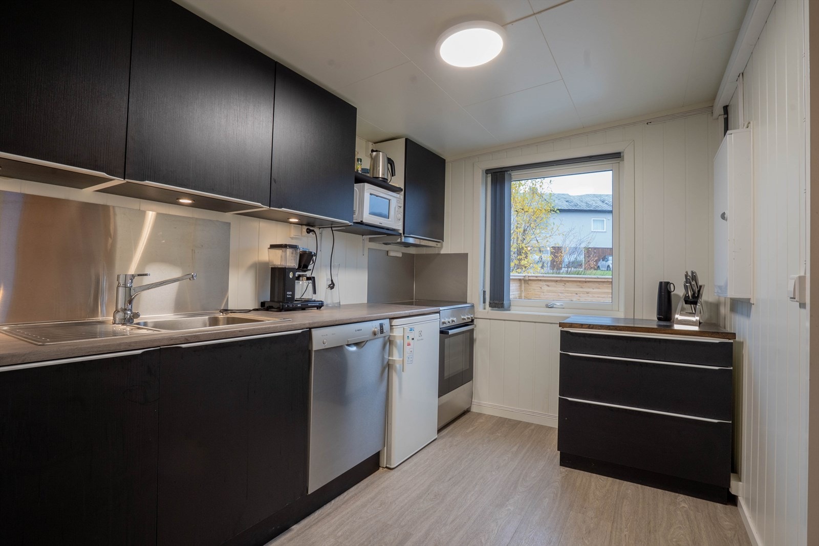 Moderne kjøkken med stilrene overflater og god benkeplass. Praktisk layout med integrerte hvitevarer. Galleribilde