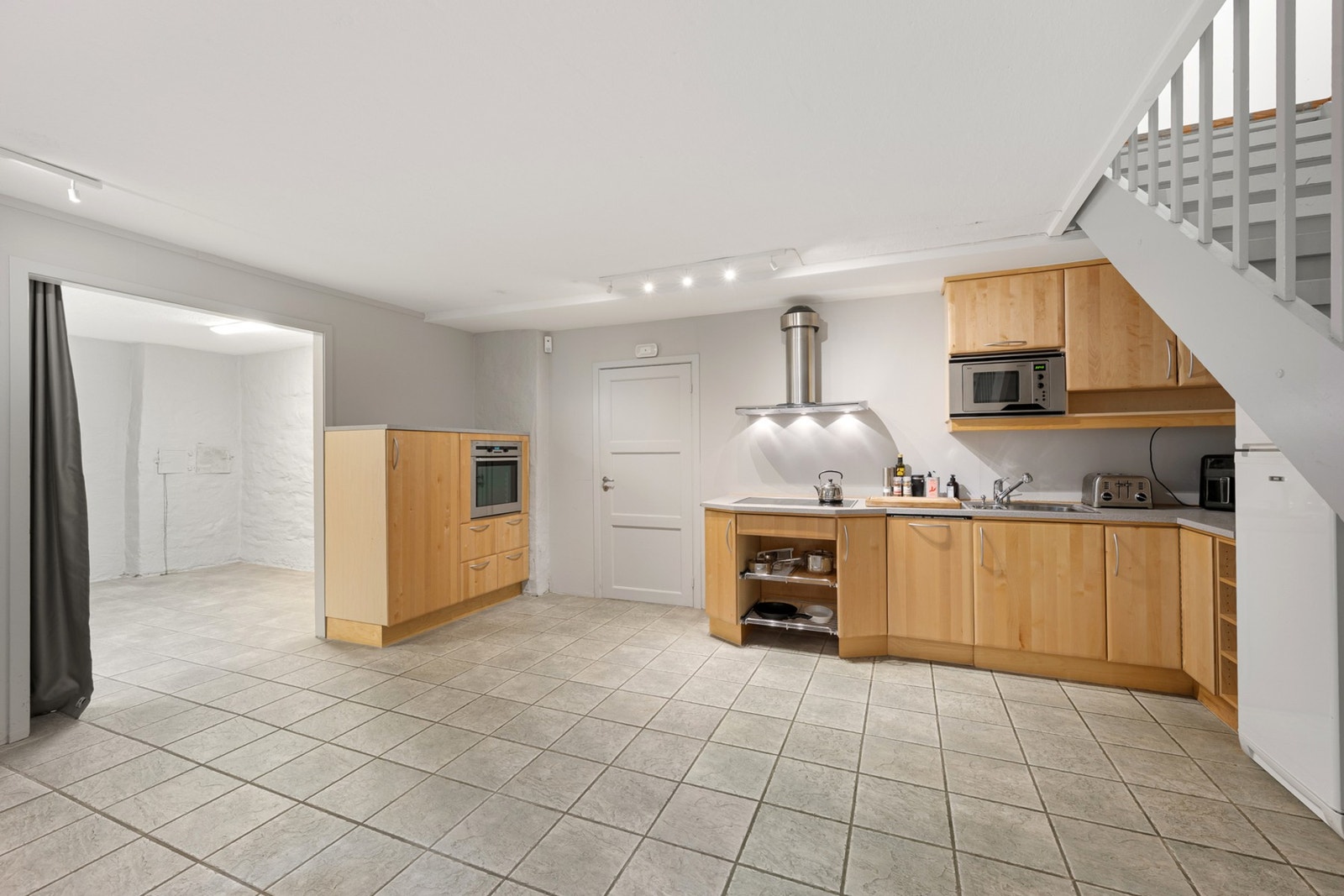 Kjøkkeninnredning har glatte fronter. Laminat benkeplate med nedfelt kum i rustfritt stål. Kullfilterventilator. Stekeovn, keramisk topp, oppvaskmaskin og mikrobølgeovn er integrert i innredningen. Galleribilde