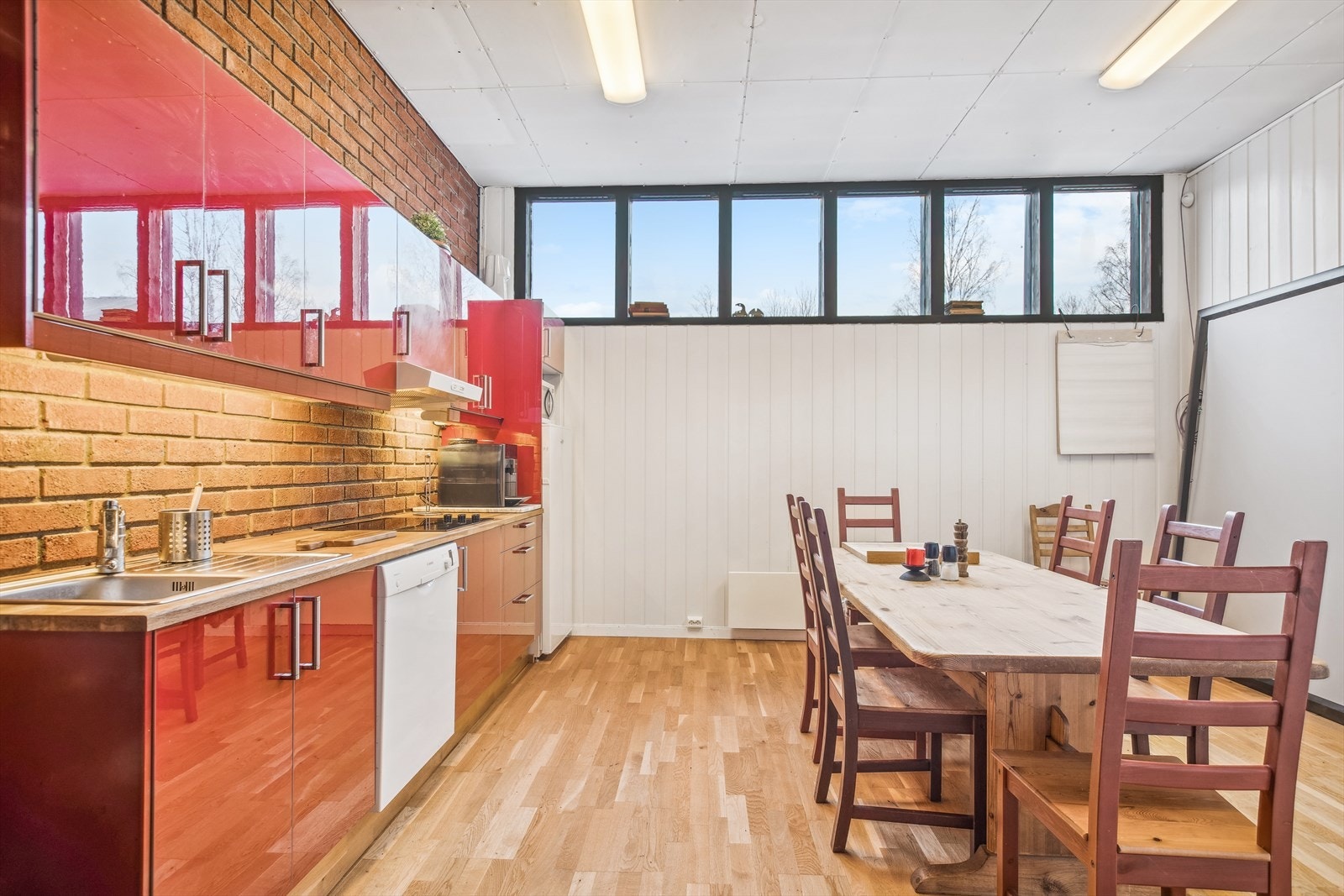 Kjøkken/spiserom med kjøkkeninnredningen langs veggen og god plass til spisebord. Det er integrert platetopp i kjøkkenet, og avsatt plass til oppvaskmaskin og kjøleskap. Galleribilde