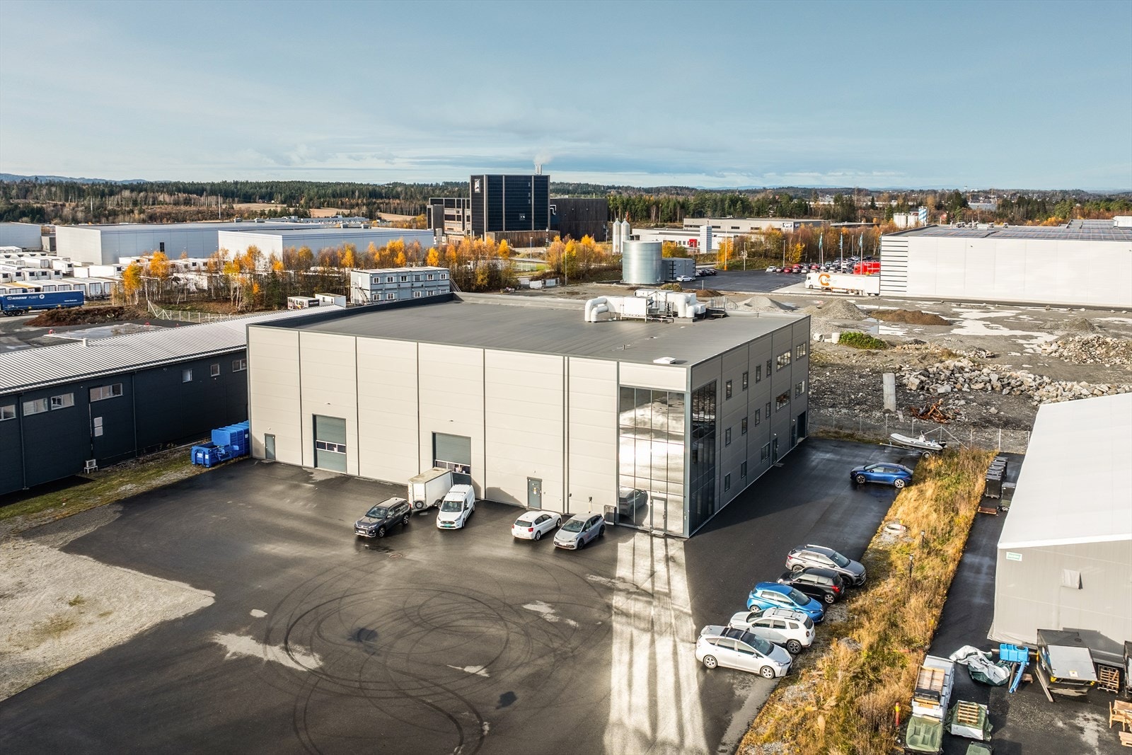 Rikelig med oppstillingsplasser med 4 ladestasjoner for elbil. Gode manøvreringsarealer for store kjøretøy til lager/verksted. Galleribilde