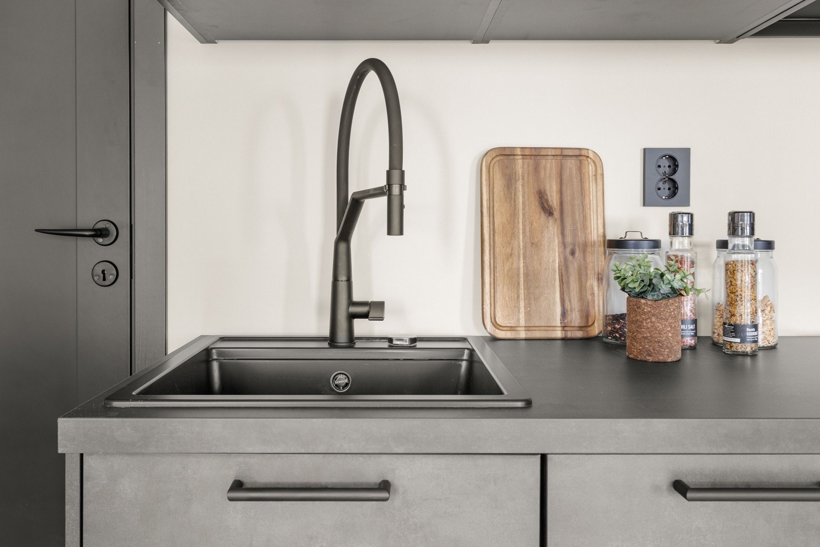 Stilrene detaljer med mørk kjøkkenarmatur og benkeplate som kompletterer det moderne uttrykket. Galleribilde