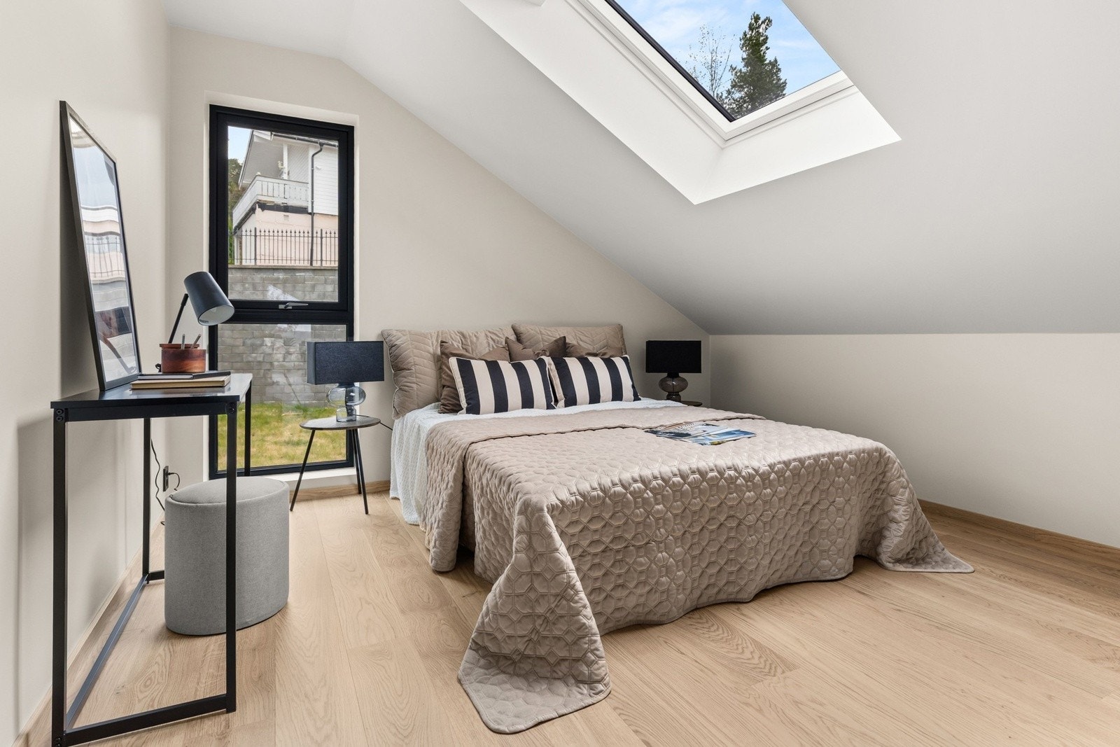 Lyst og tiltalende soverom med store vindusflater og takvindu som gir rommet en luftig og behagelig atmosfære. Galleribilde