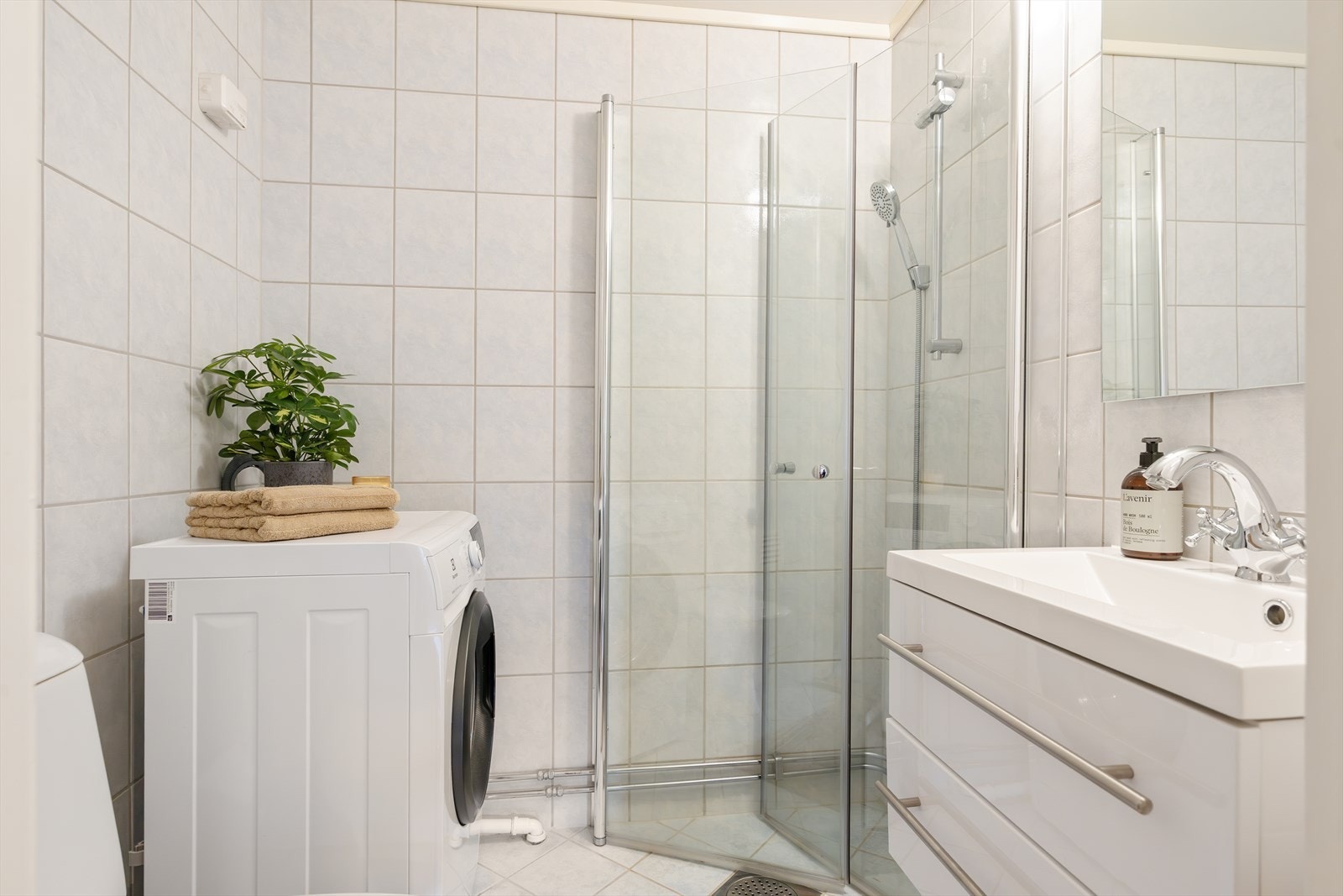 Baderommet er innredet med klosett, servantskap med glatte høyglansfronter, speil og dusjhjørne. Det er naturlig avtrekksventilasjon og opplegg for vaskemaskin. Galleribilde