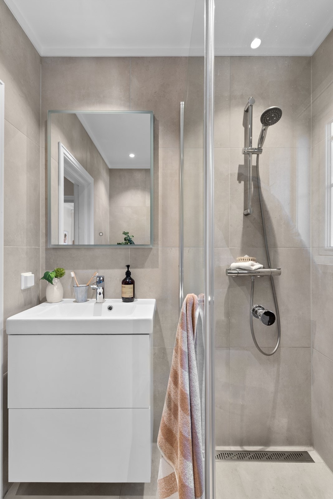 Badet er utstyrt med vegghengt toalett, servant med servantskap, svingbare dusjvegger og nedsenket dusjhjørne. Galleribilde