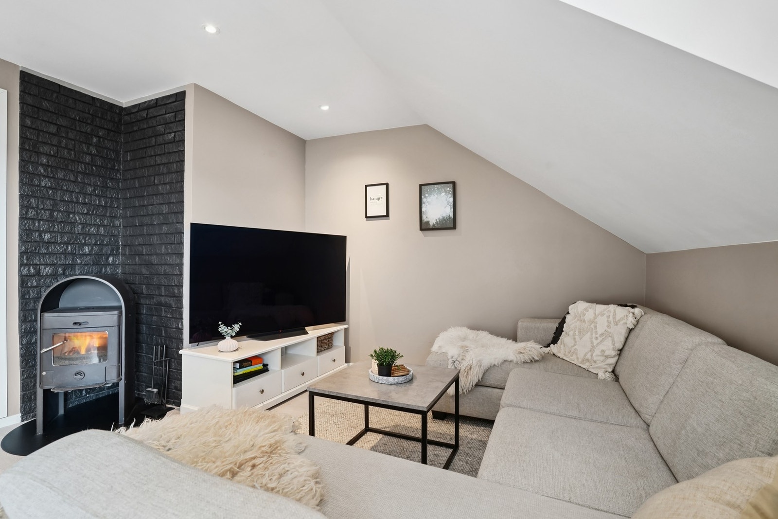 Det er god plass til hjørnesofa på stuen. Det er montert vedovn stående på stålplate. Galleribilde