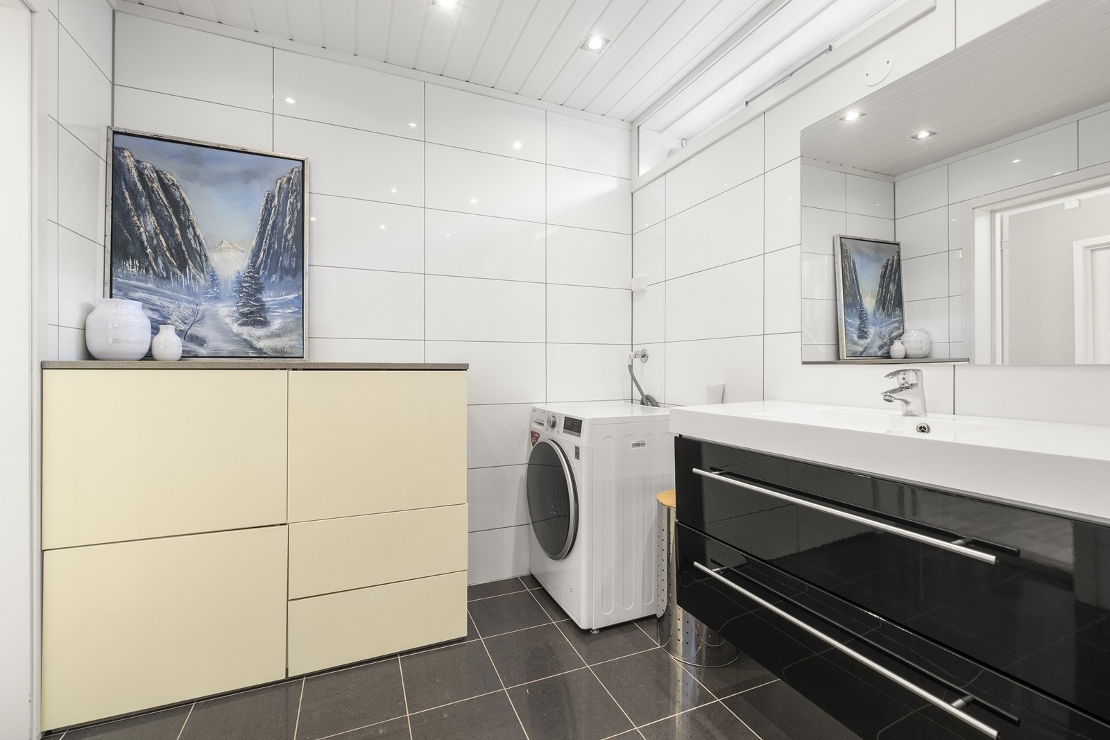 Badet er utstyrt med vegghengt toalett, servant med skuffer og dusjnisje med innfellbare glassdører. Galleribilde