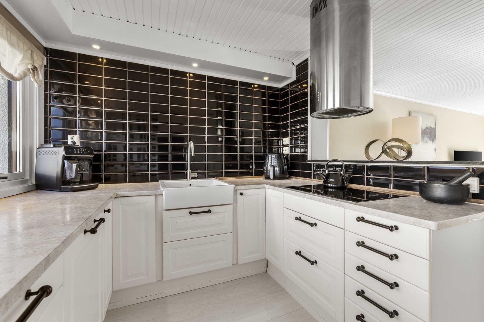 Innredningen oppleves klassisk med hvite, profilerte fronter, laminat benkeplate og svarte håndtak. Galleribilde