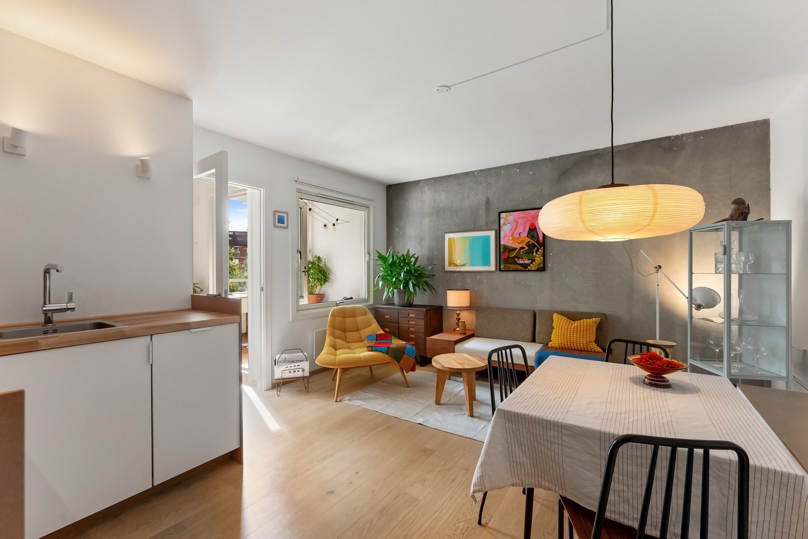 Leiligheten har en lys og luftig stue med store vindusflater som gir rikelig med naturlig lysinnslipp. Rommet i likhet med resten av boligen er malt i lyse farger, med unik eksponert betongvegg for et robust uttrykk Galleribilde