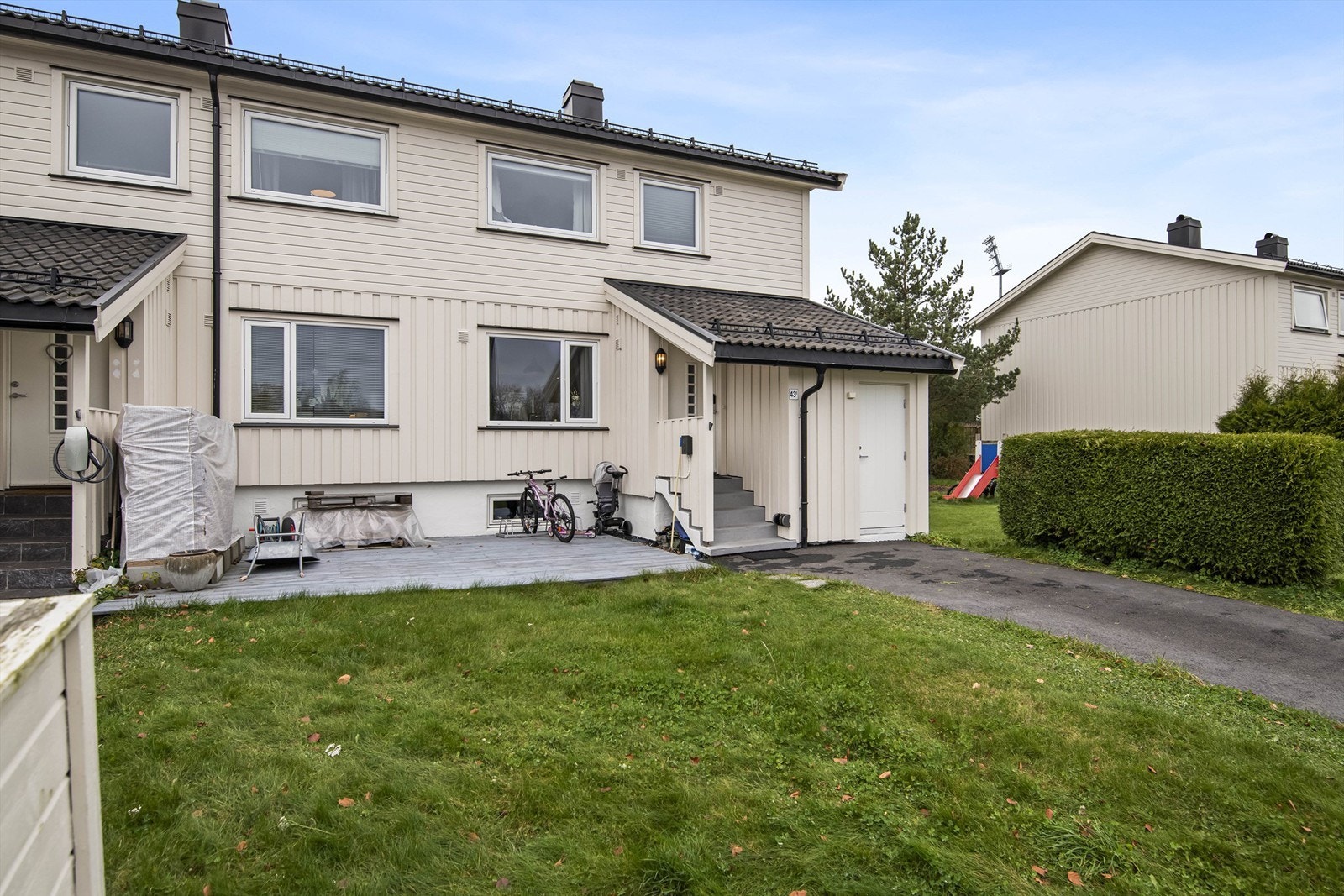 Asfaltert gårdsplass med elbillader montert på veggen Galleribilde