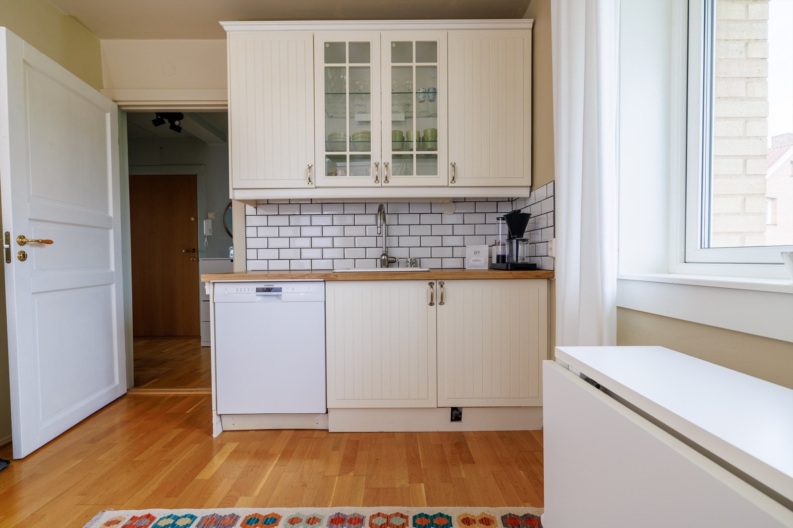 Det er fliser over benkeskapet og integrerte hvitevarer som induksjonstopp og stekeovn. Galleribilde