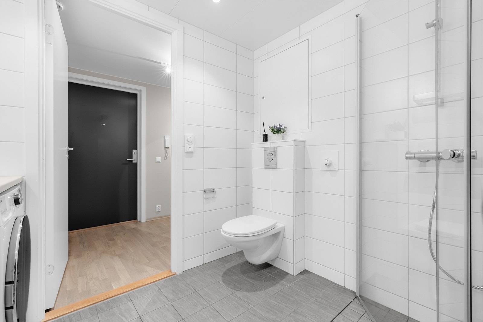 Badet er utstyrt med vegghengt toalett, avtrekk tilkoblet ventilasjonsanlegget og gjennomført flislagte overflater for et helhetlig uttrykk. Galleribilde