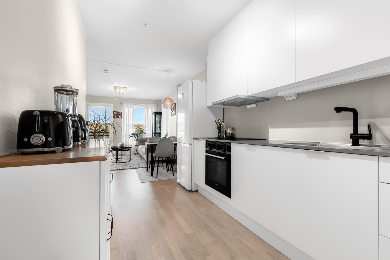 Moderne kjøkkeninnredning med laminerte skrog, slette fronter og laminat benkeplate med nedfelt oppvaskkum. Løsningen gir et stilrent og funksjonelt uttrykk. Galleribilde