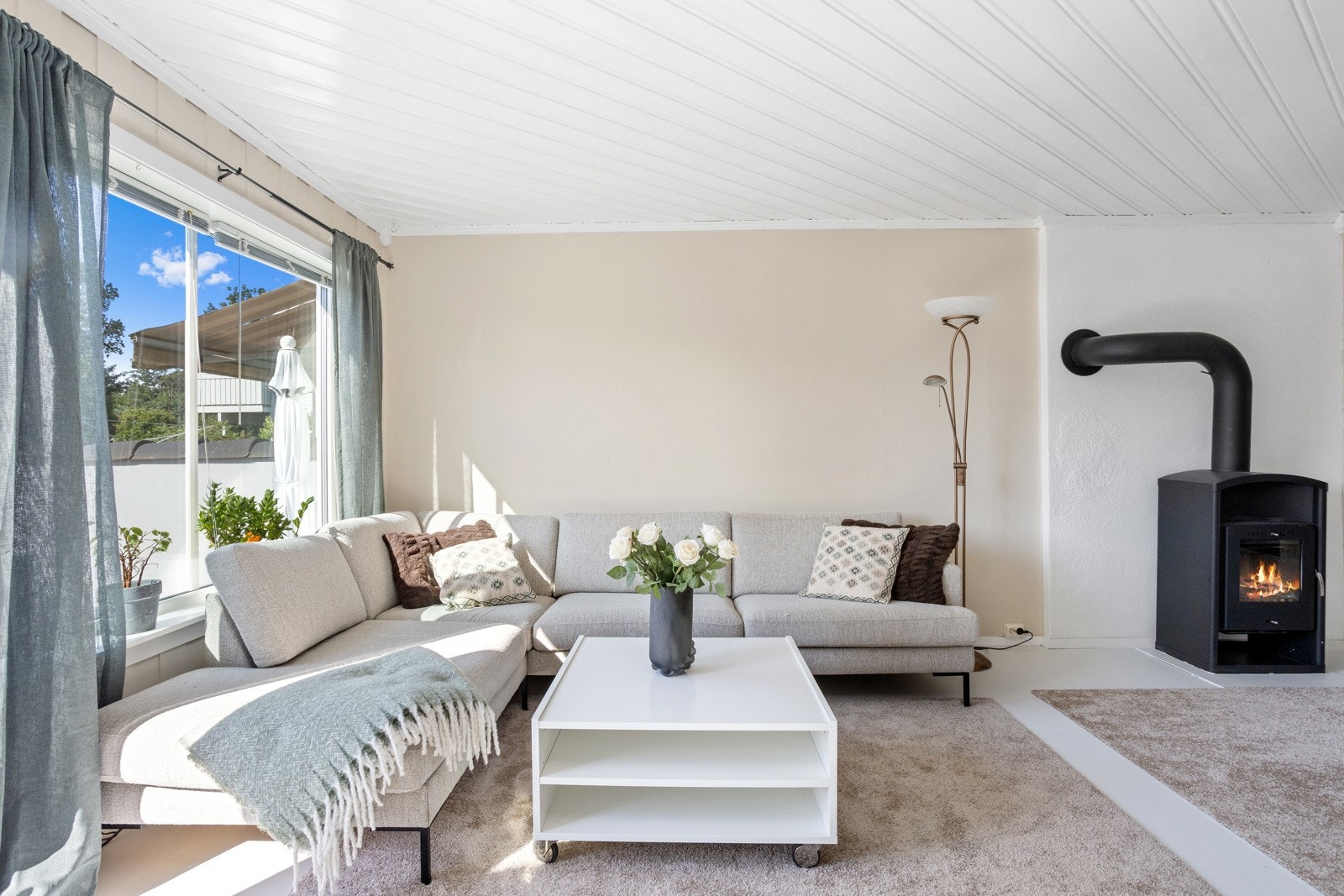 Boligen har lyse pene overflater med store vinduer og peisovn. Galleribilde