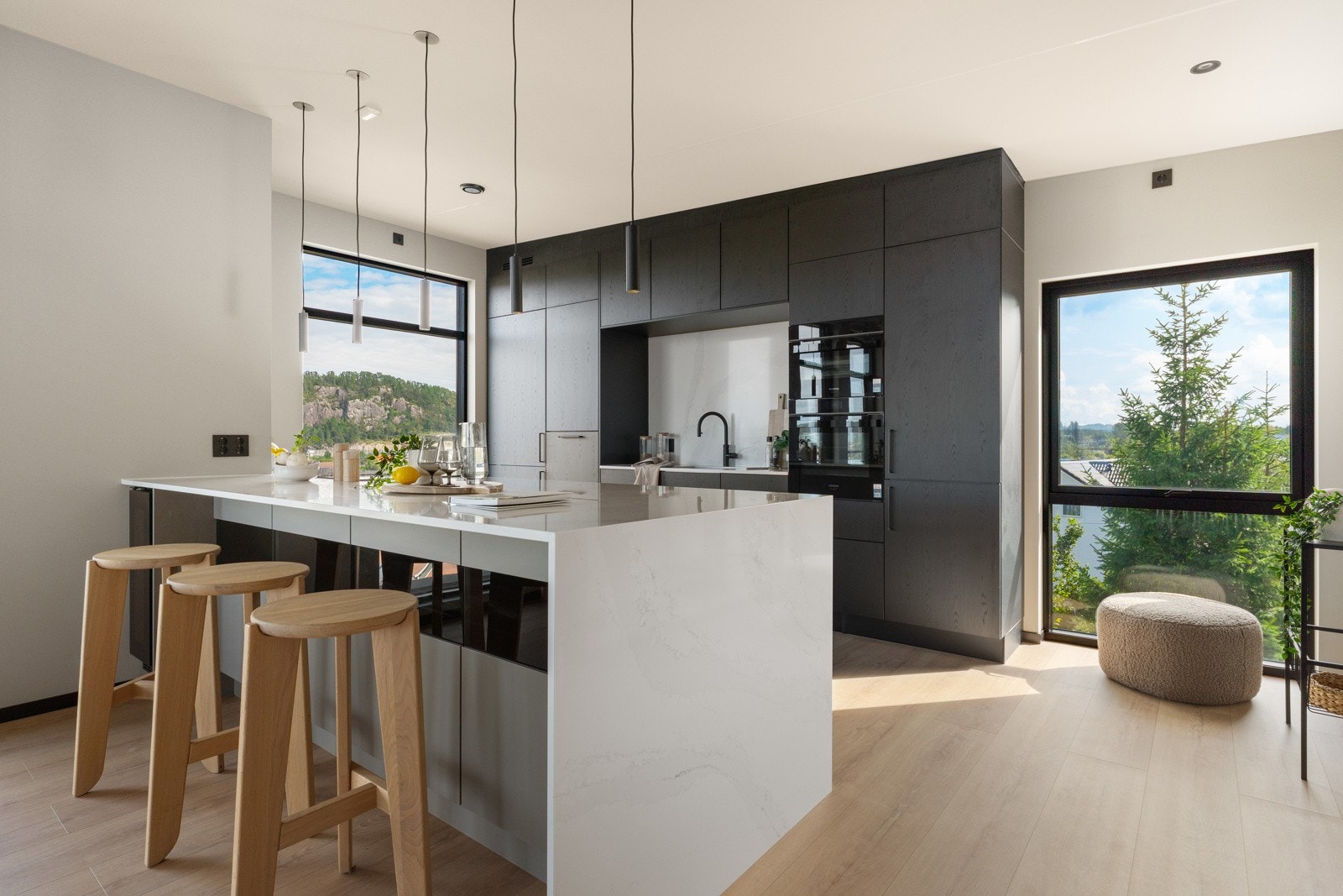 Kjøkkenet er innredet med svarte og hvite, samt glatte fronter og benkeplate i stein med planlimt kjøkkenvask. Galleribilde