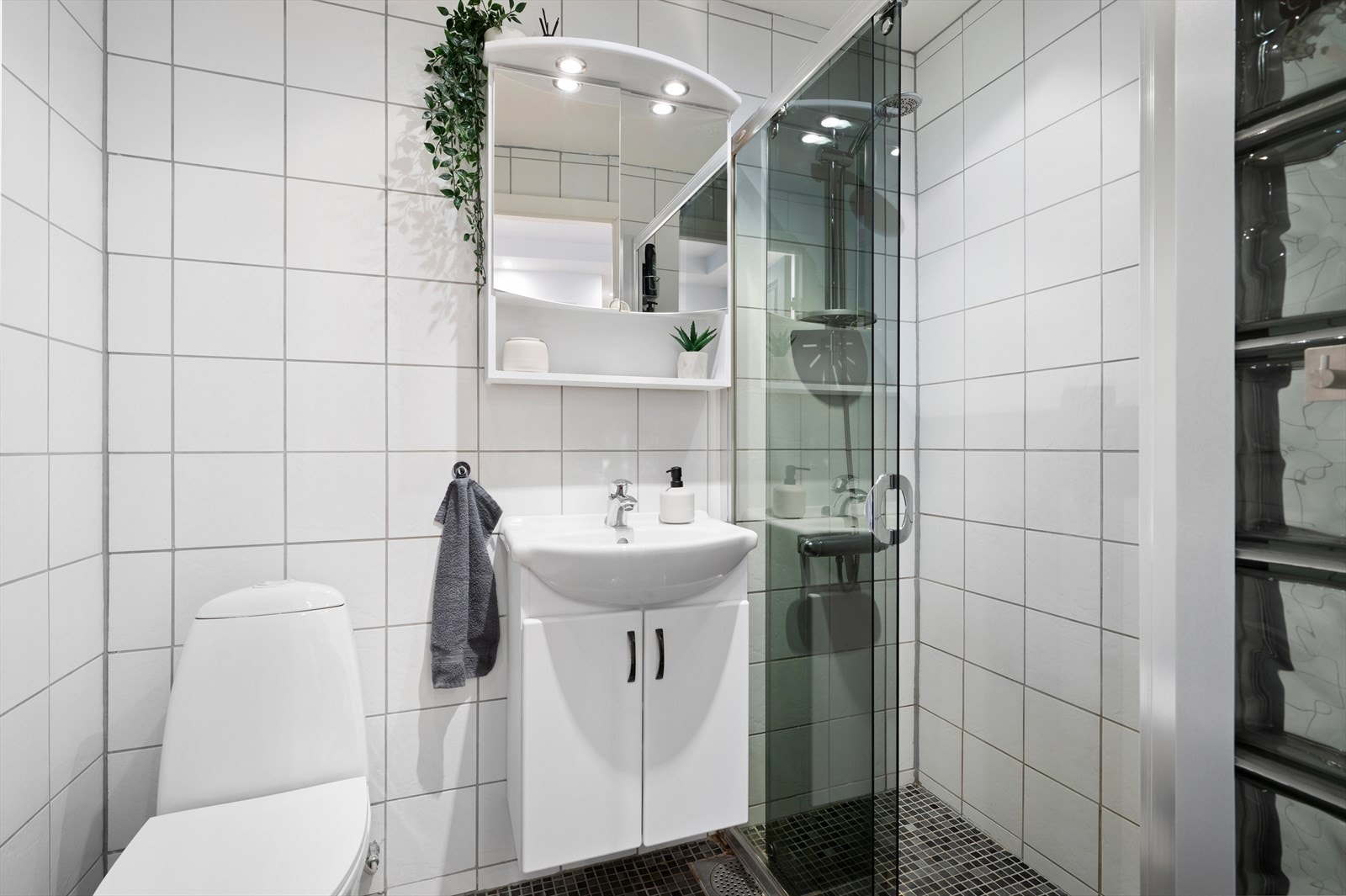 Pent flislagt bed med varmekabler i gulv. Innredet med dusjsone, WC, servantskap og speil. Galleribilde