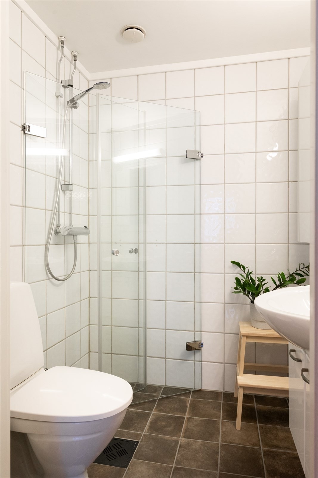 Badet er innredet med toalett, servant nedfelt i innredning, vegghengt skap og dusjhjørne med svingbare glassdører. Galleribilde