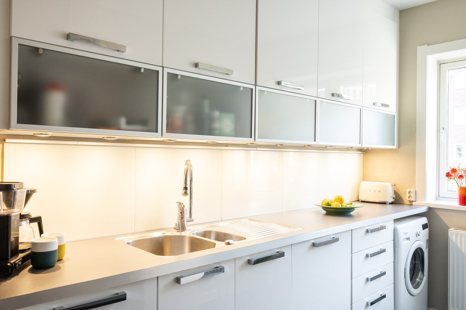 Kjøkkeninnredningen består av hvite glatte fronter og benkeplate av laminat med nedfelt vaskekum. Galleribilde