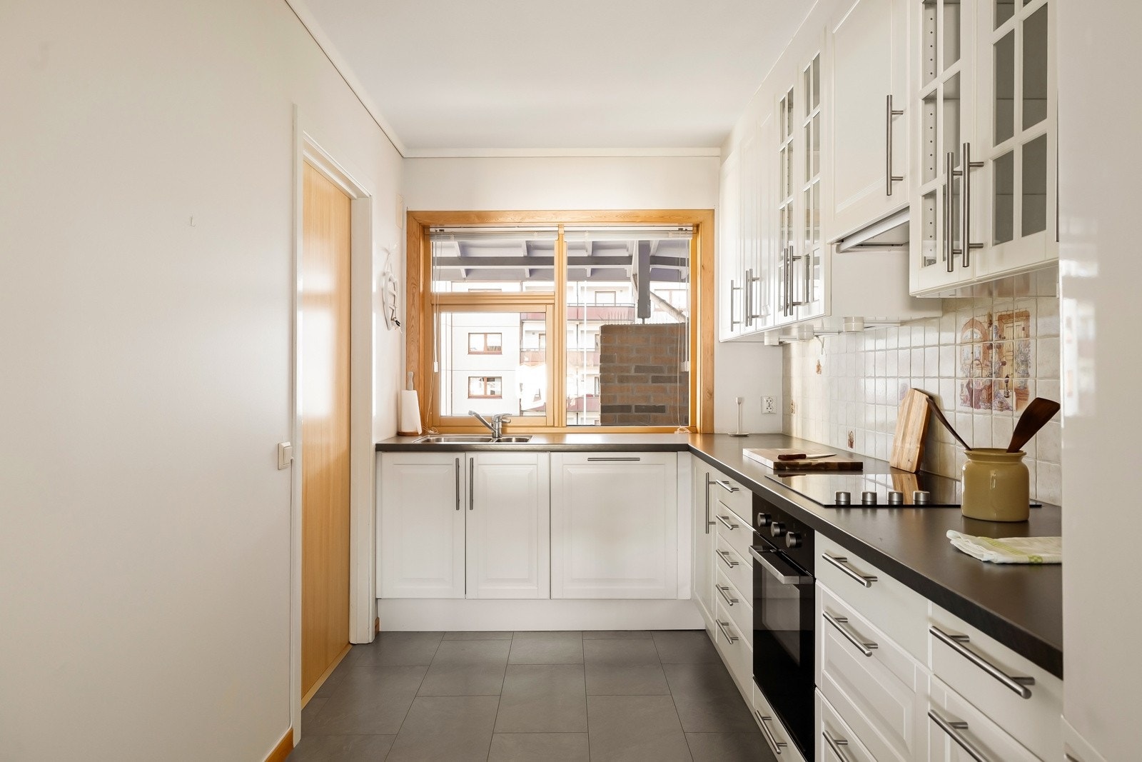 Det lyse kjøkkenet har et klassisk utrrykk med profilerte fronter, glassinnfelling og mørk benkeplate. Galleribilde