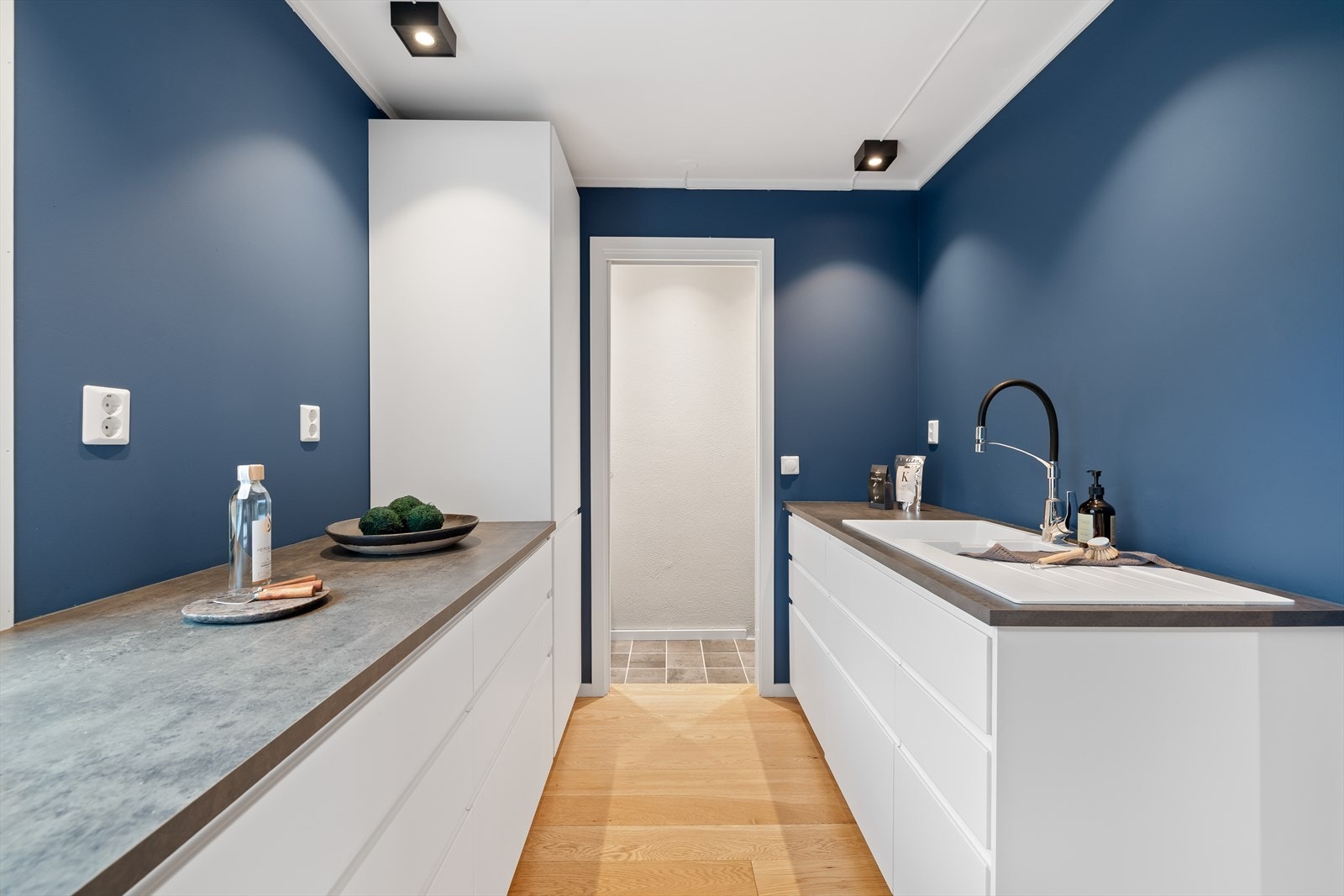 Innredningen har glatte fronter og laminert benkeplate med nedfelt kum. Det er godt med skap- og benkeplass, og kjøkkenet er utstyrt med integrert oppvaskmaskin og kjøl-/fryseskap, samt frittstående stekeovn med platetopp og ventilator med kullfilter. Galleribilde