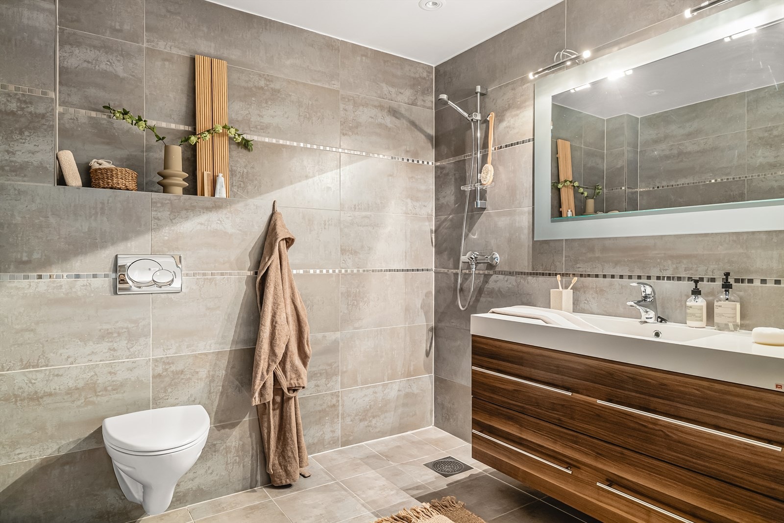 Gjestebaderommet fremstår innbydende, med helflisete overflater og behagelig gulvvarme. Galleribilde