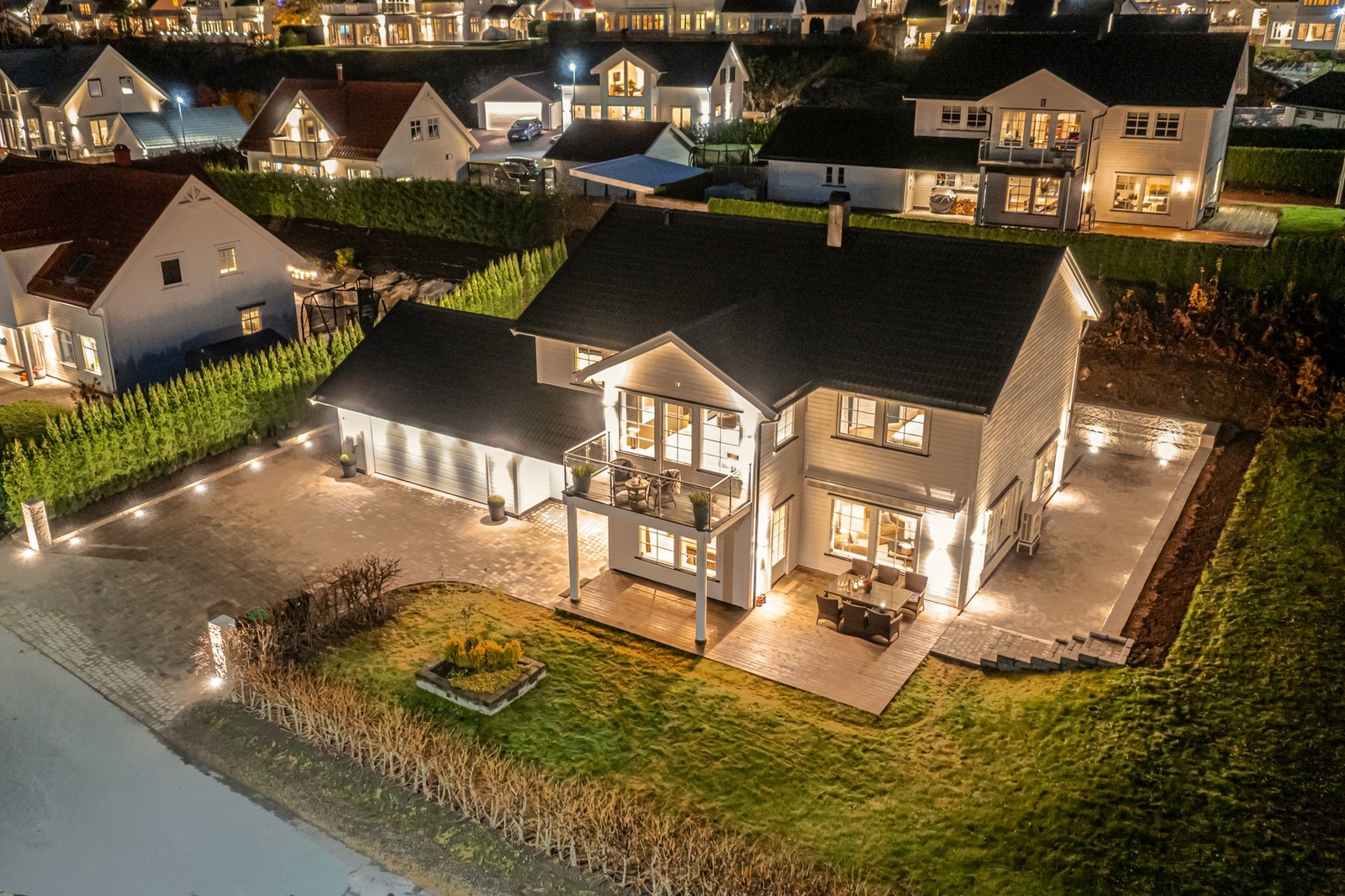 Utebelysning og moderne detaljer fremhever boligens arkitektur på en smakfull måte. Galleribilde