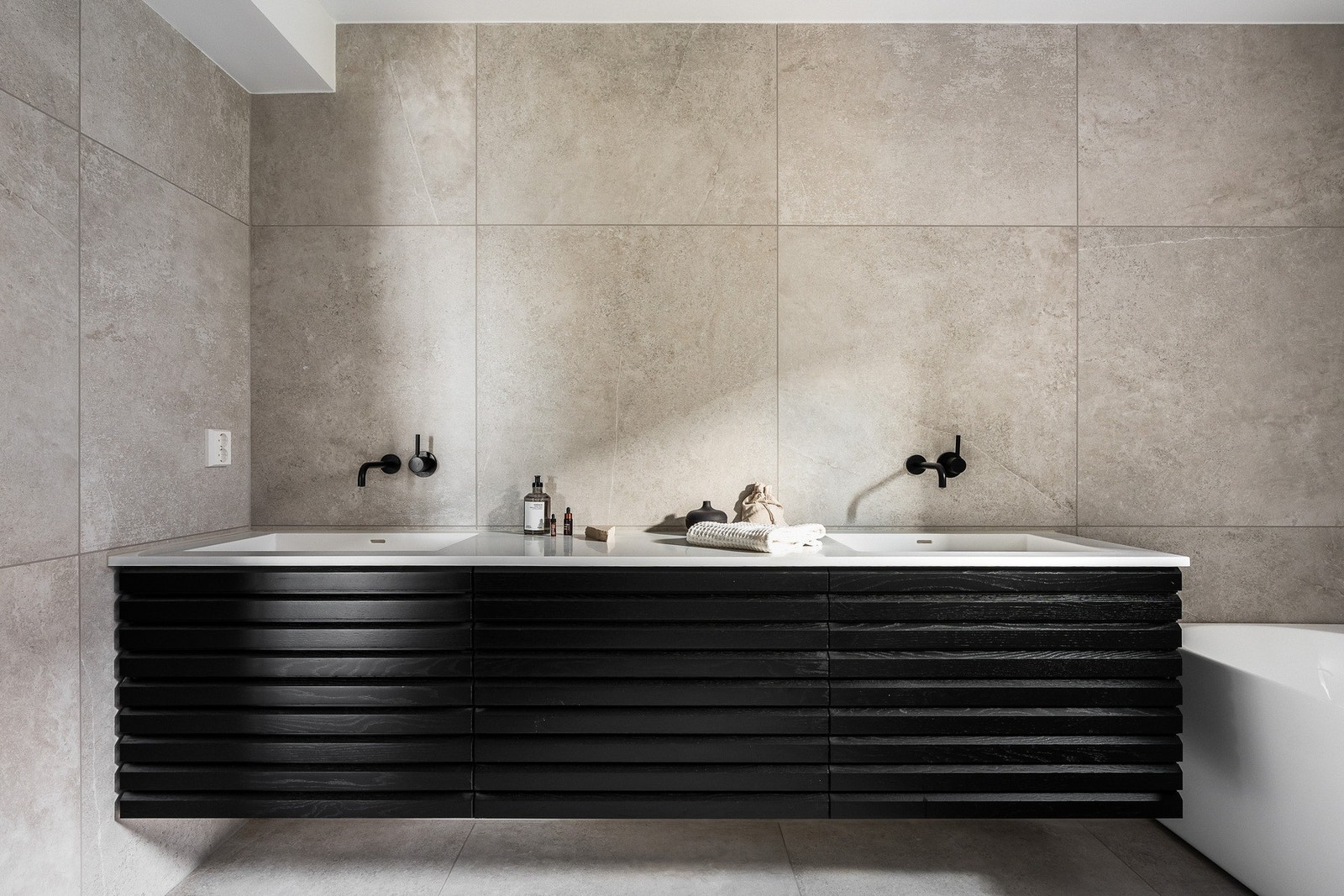 Badet er innredet med svart baderomsinnredning fra HTH, med spilepreg og heldekkende servantplate, hvor overflatene kombinerer funksjonalitet og design på en elegant måte. Galleribilde