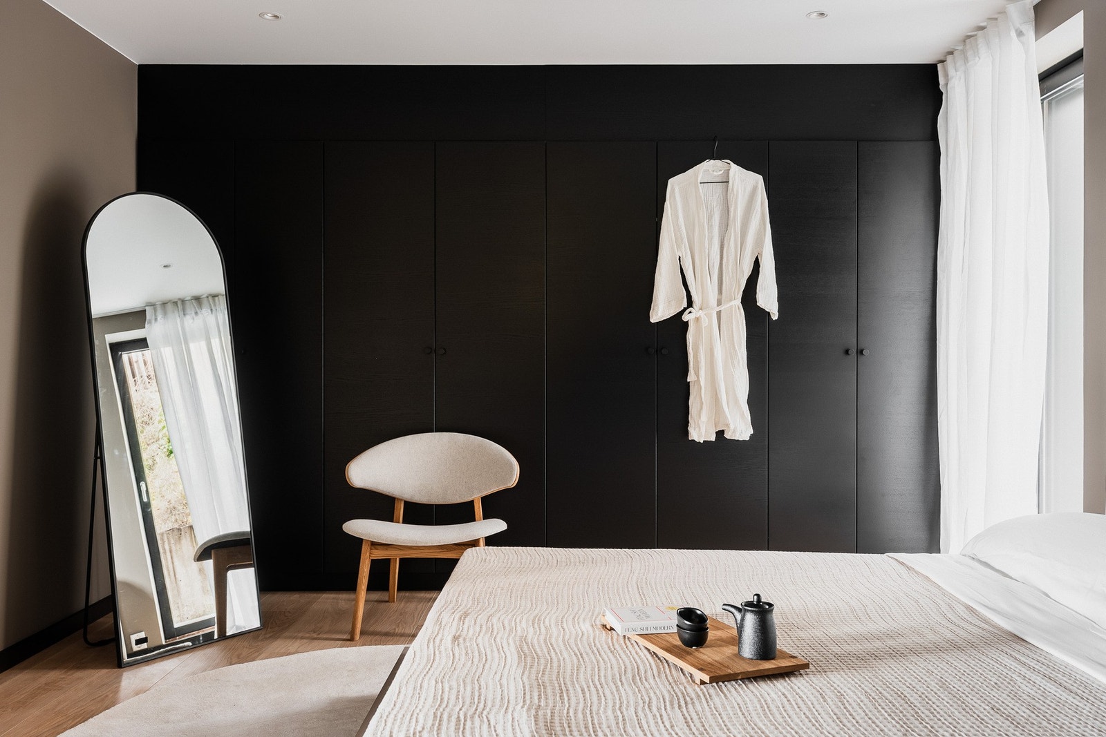 En hel vegg er innredet med plassbygde garderobeskap i sort utførelse (HTH) som tilfører både eksklusivitet og praktisk oppbevaring. Galleribilde