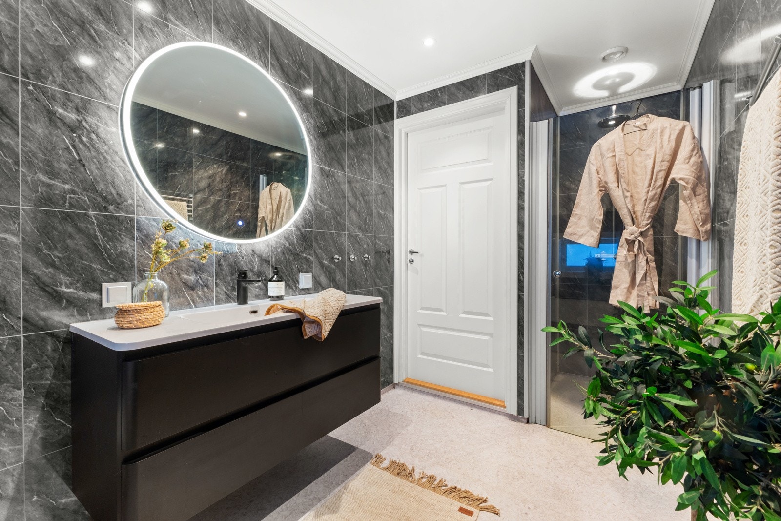 Veggene er kledd med baderomsplater, og taket er malt med downlight-belysning for en moderne følelse. Gulvet har vinylbelegg, og panelovn er plassert under vinduet. Det er også mekanisk avtrekk fra våtrom for god ventilasjon. Galleribilde