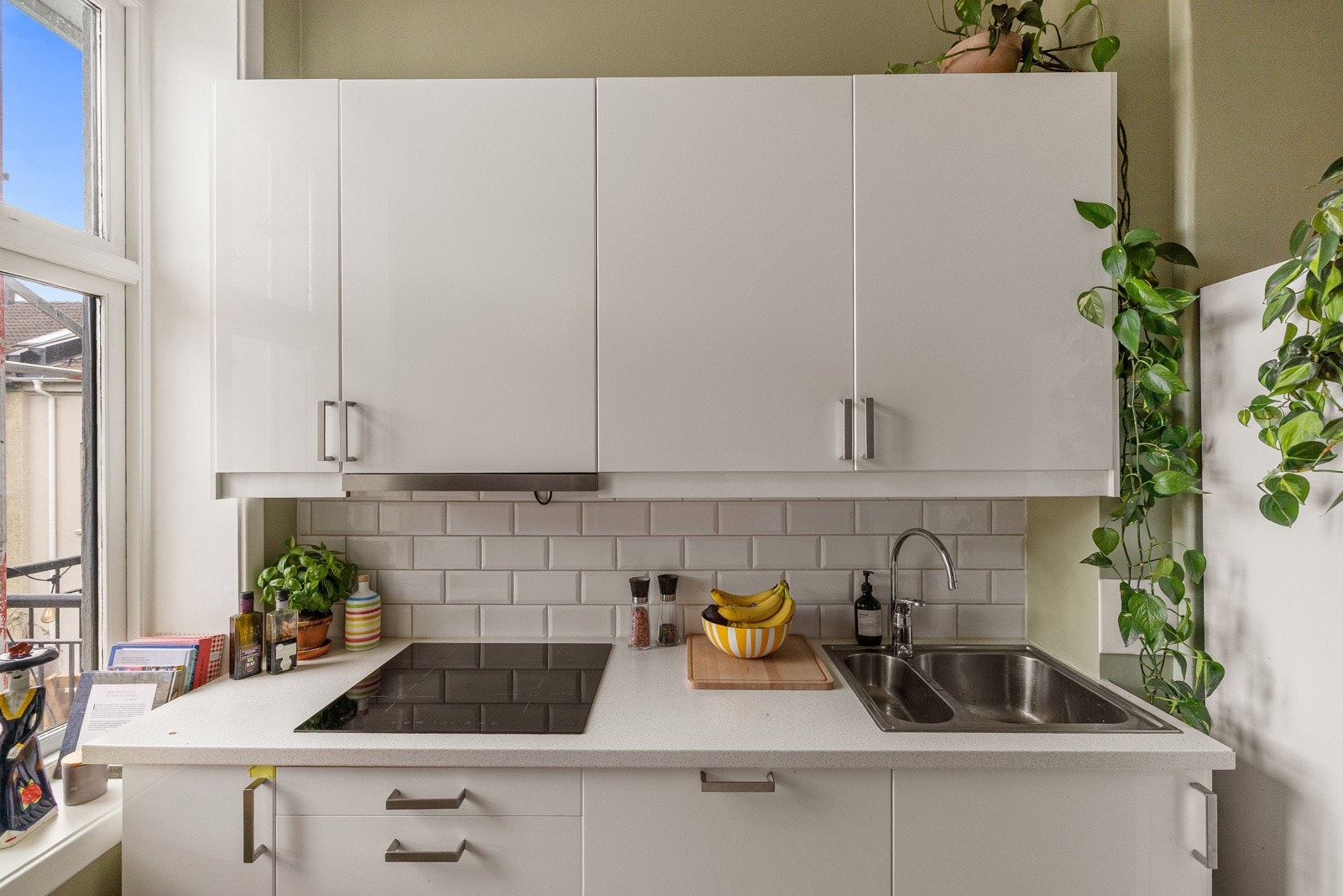 Lys og moderne kjøkkeninnredning med god skap- og benkeplass. Innredningen har hvite glatte fronter og laminert benkeplate med nedfelt oppvaskkum. Både fint og praktisk med lekre fliser i benkeryggen. Galleribilde