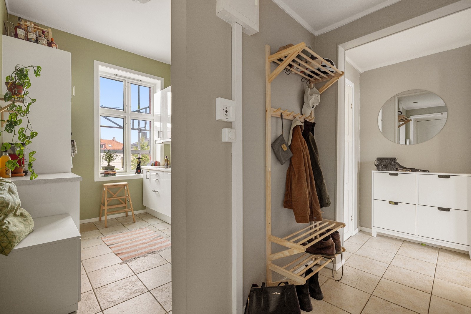 Du ønskes velkommen inn i en lys og praktisk entré med plass til sko og oppheng av yttertøy. Entréen har lyse fliser på gulv med gulvvarme og glatte overflater malt i en fin farge. Sikringsskap med automatsikringer montert på vegg. Galleribilde