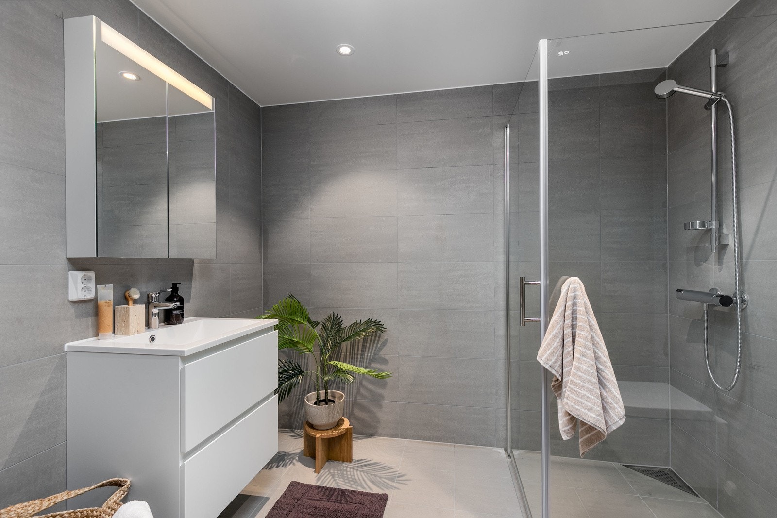 Pent flislagt bad med vannbåren varme i gulv. Innredningen består av en benkeinnredning med skuffer og servant, samt speil med integrert lys over servant. Galleribilde