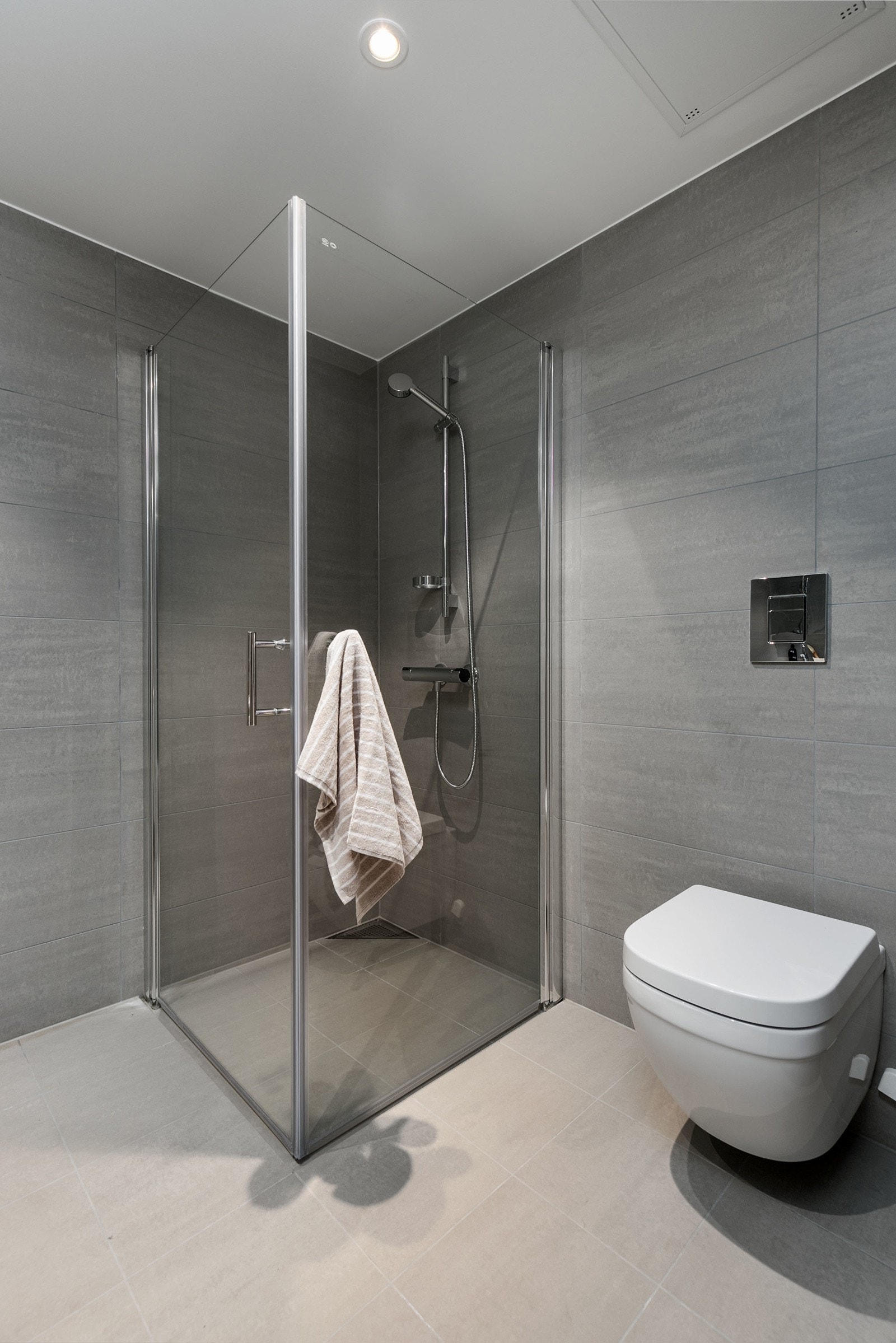 Videre er badet utstyrt med dusjhjørne i herdet glass og veggfestet toalett. Opplegg for vaskemaskin. Galleribilde