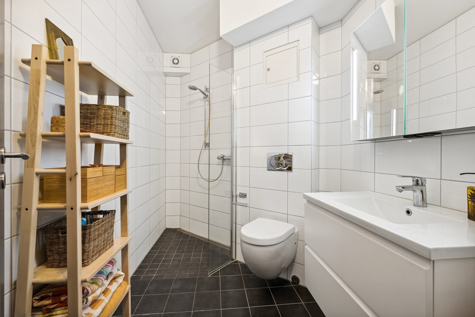 Lekkert, flislagt baderom fra 2019 med vegghengt toalett, dusjhjørne og servant. Det er downlights i himling. Galleribilde